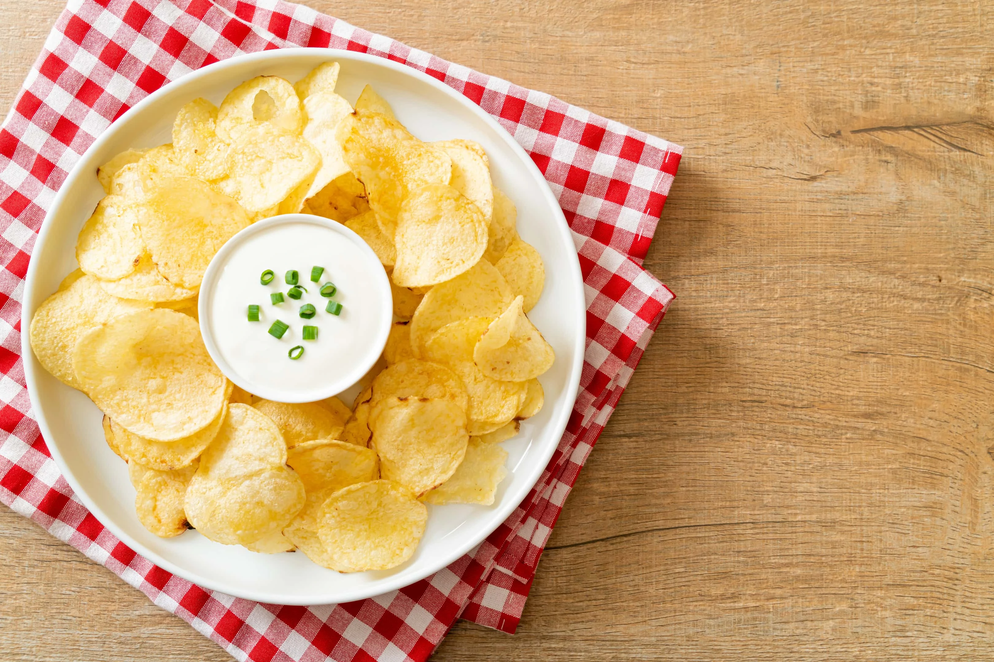 Potato chips with sour cream dipping sauce on a plate