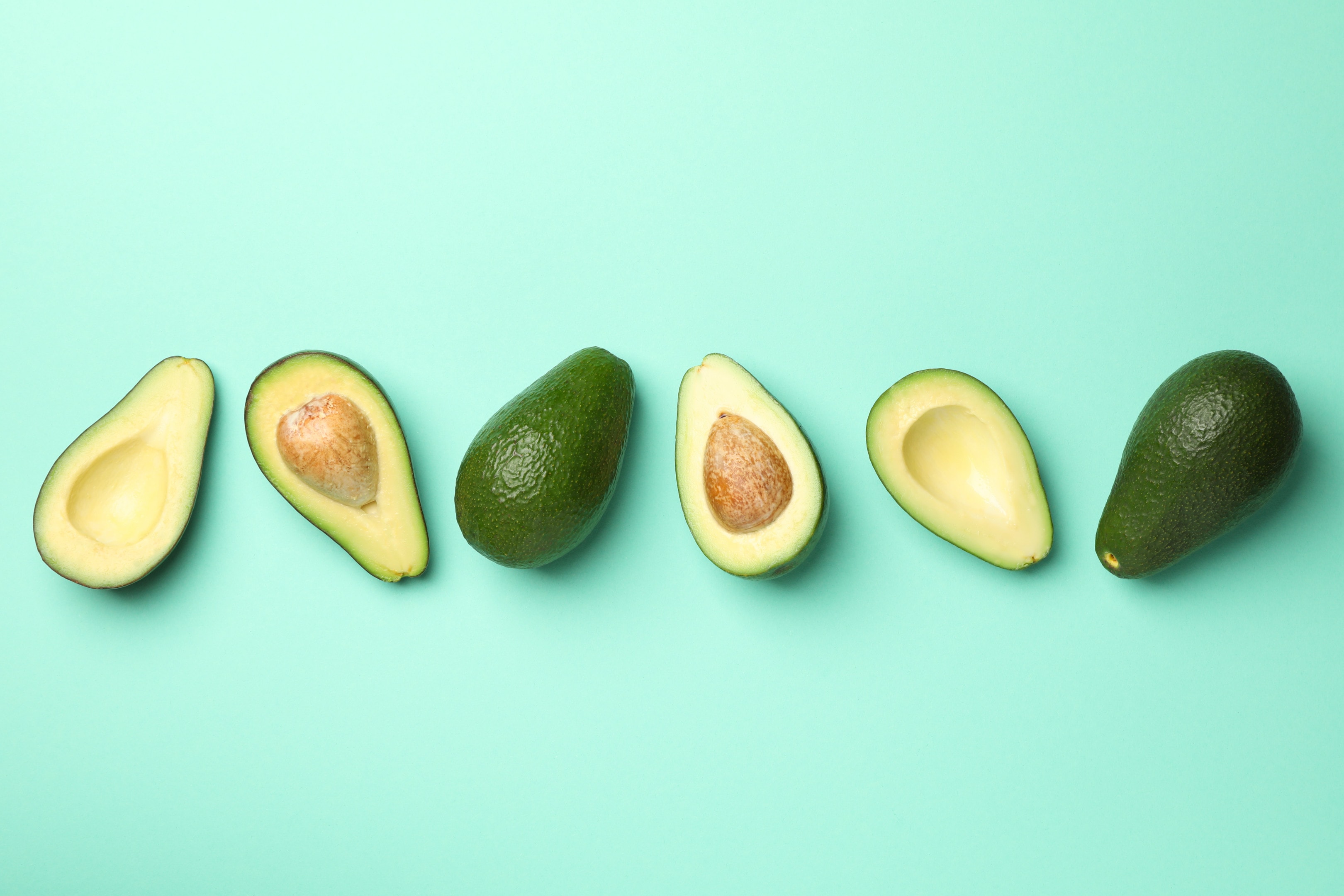 Ripe fresh avocado on mint background