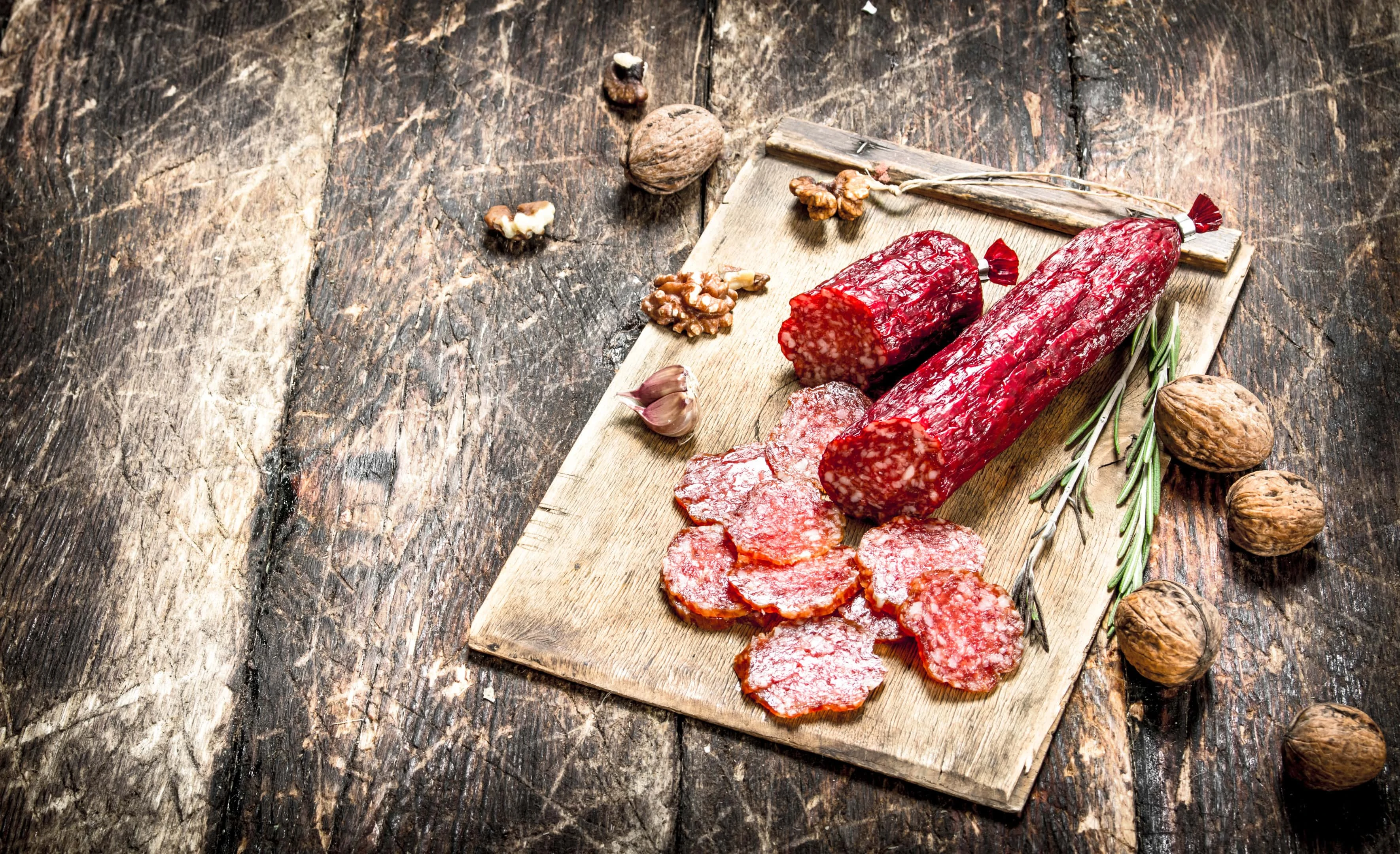 Salami with spices and nuts on wooden board