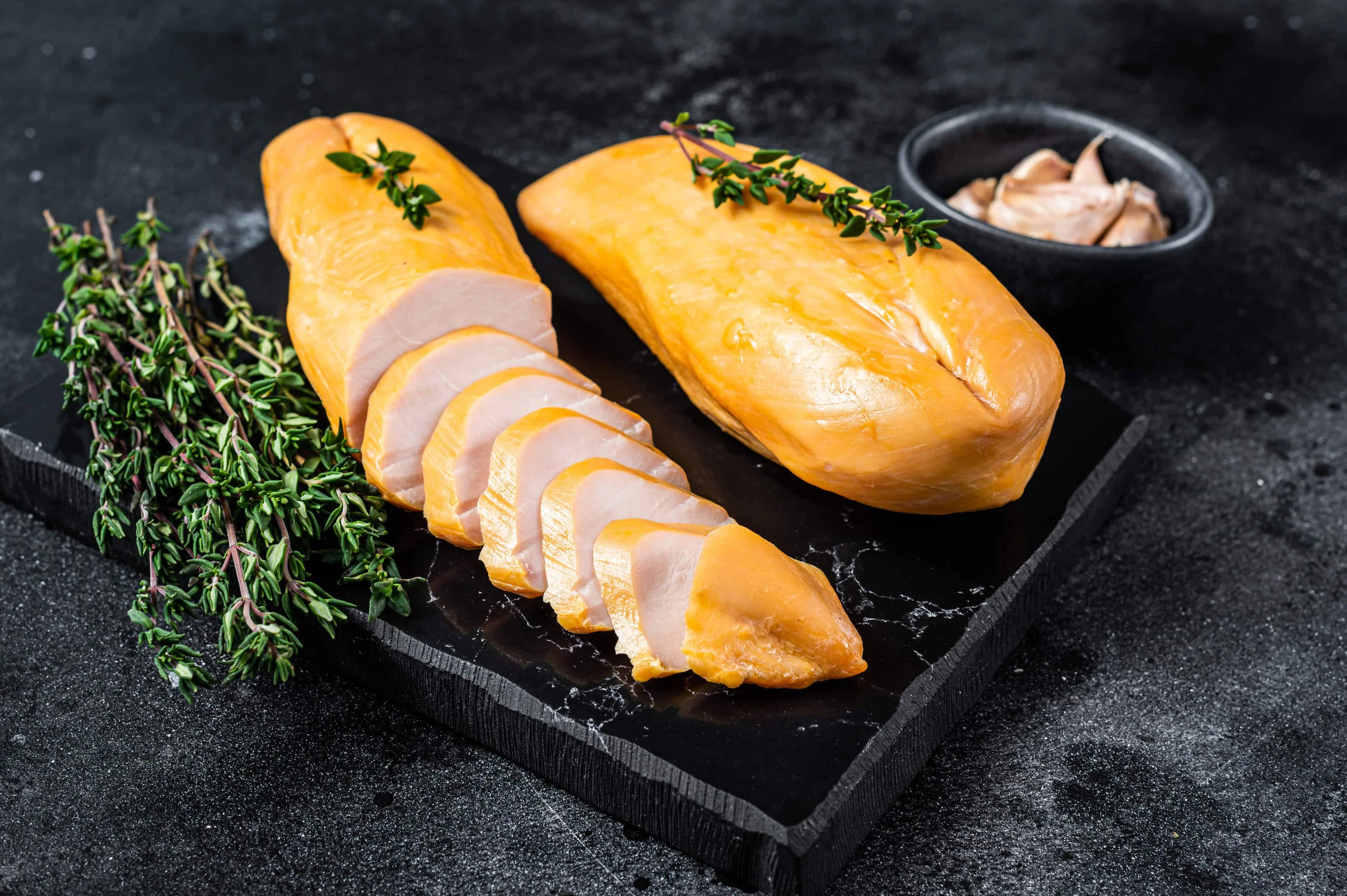 Smoked cut of chicken breast fillet on black table