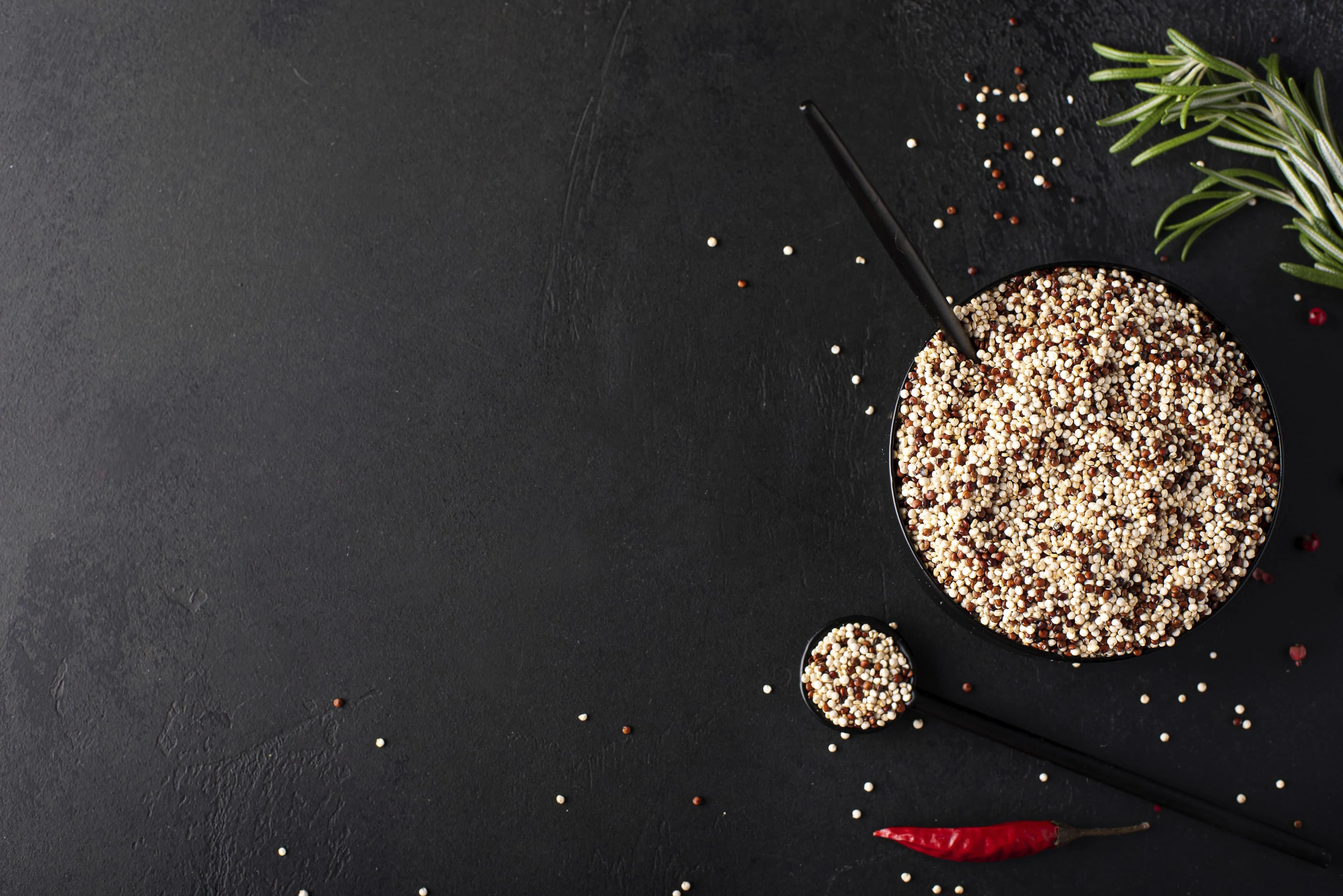 White and red quinoa grits with spices in black bowl