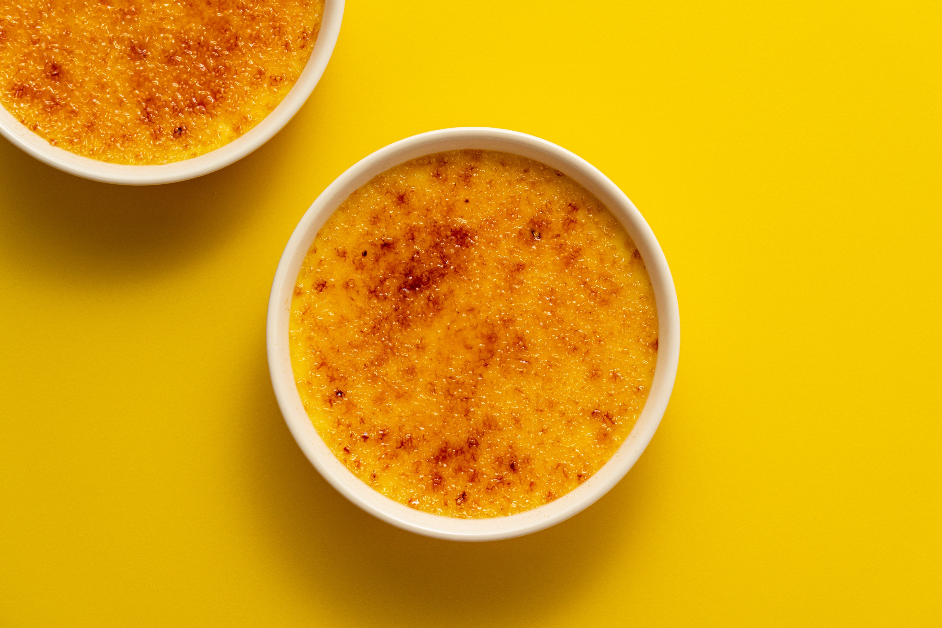 Creme brulee with brown sugar on bright yellow background
