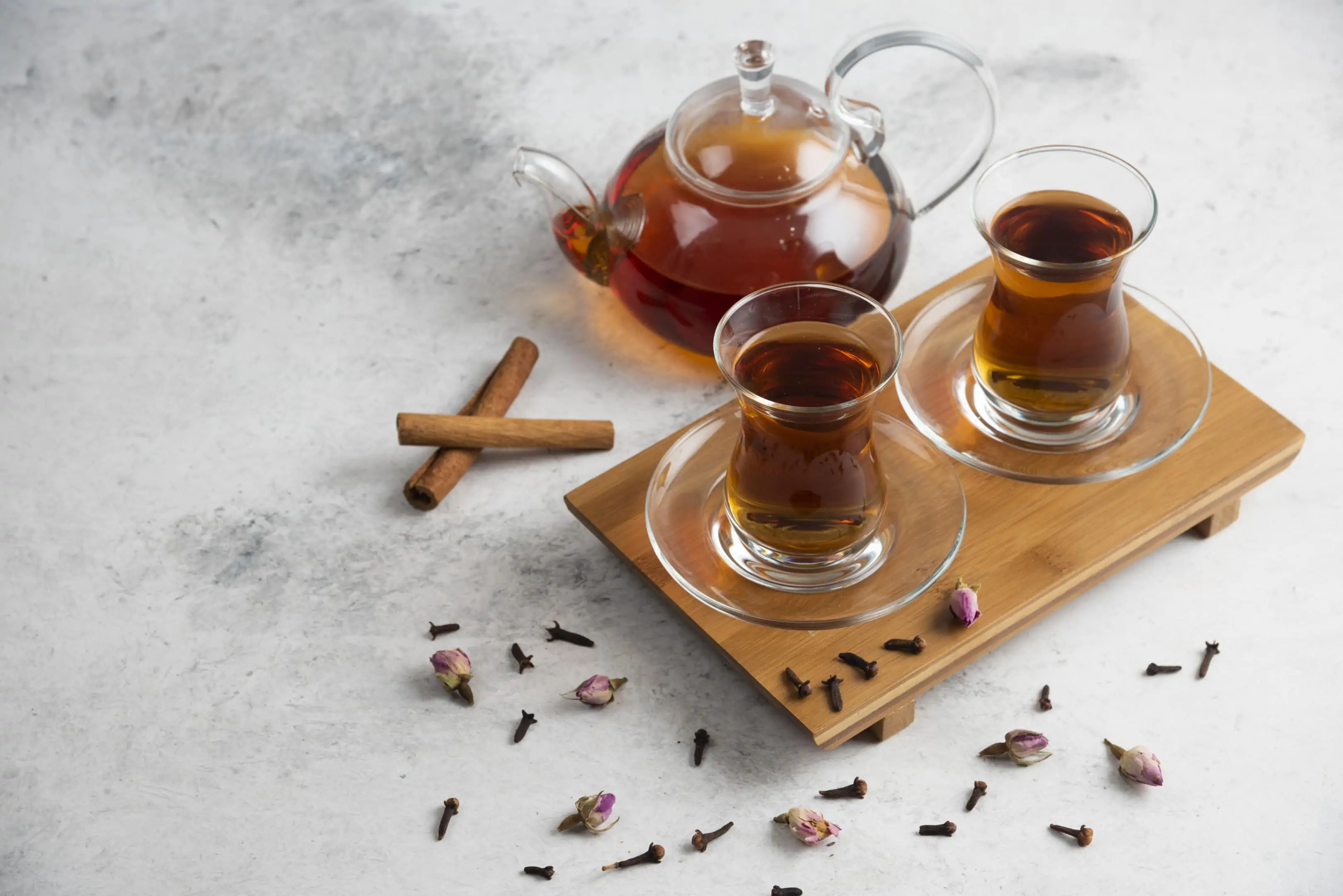 Cups of tea with cloves cinnamon sticks and dried roses