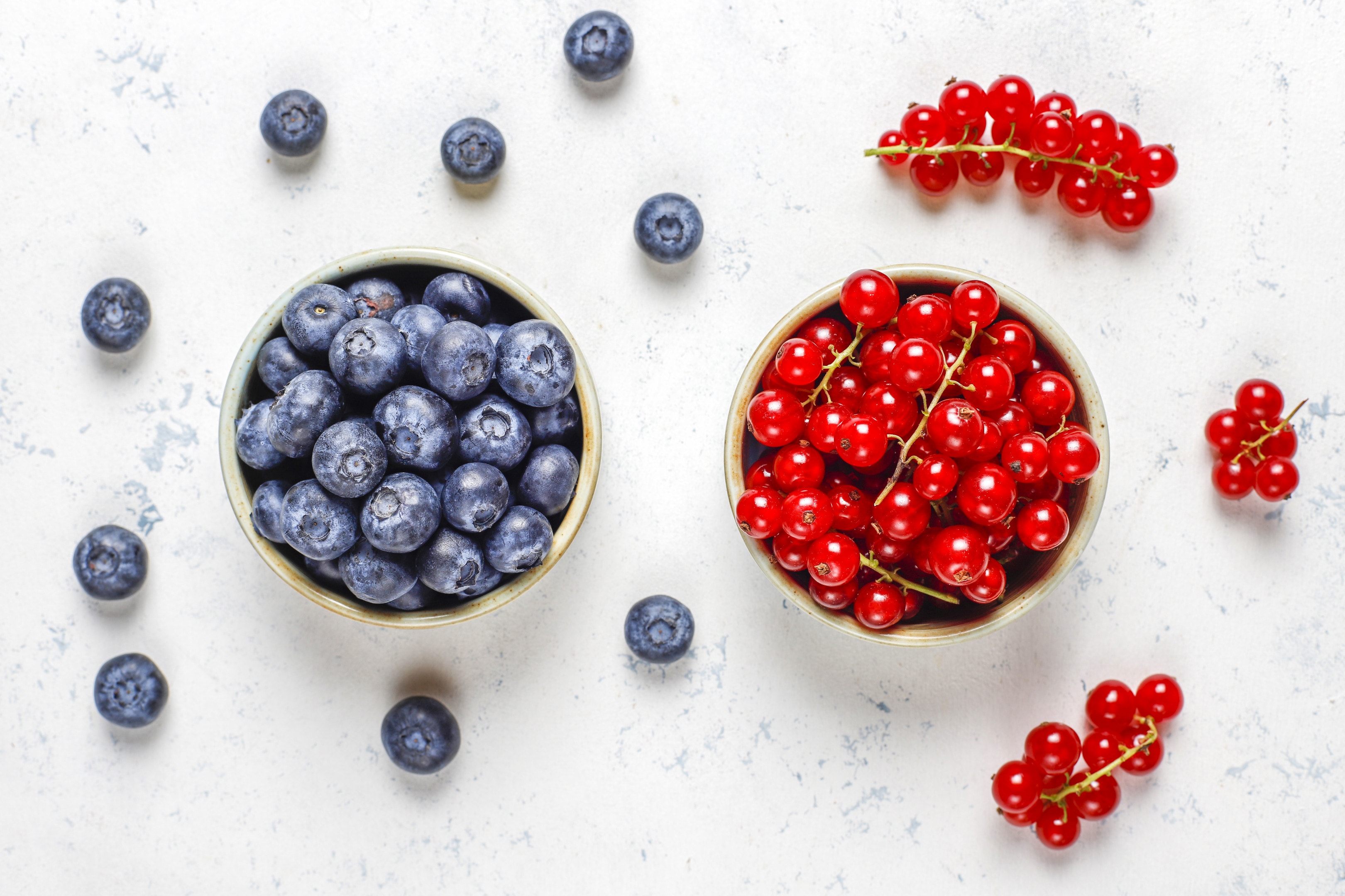 Fresh blueberries and cranberries on white table