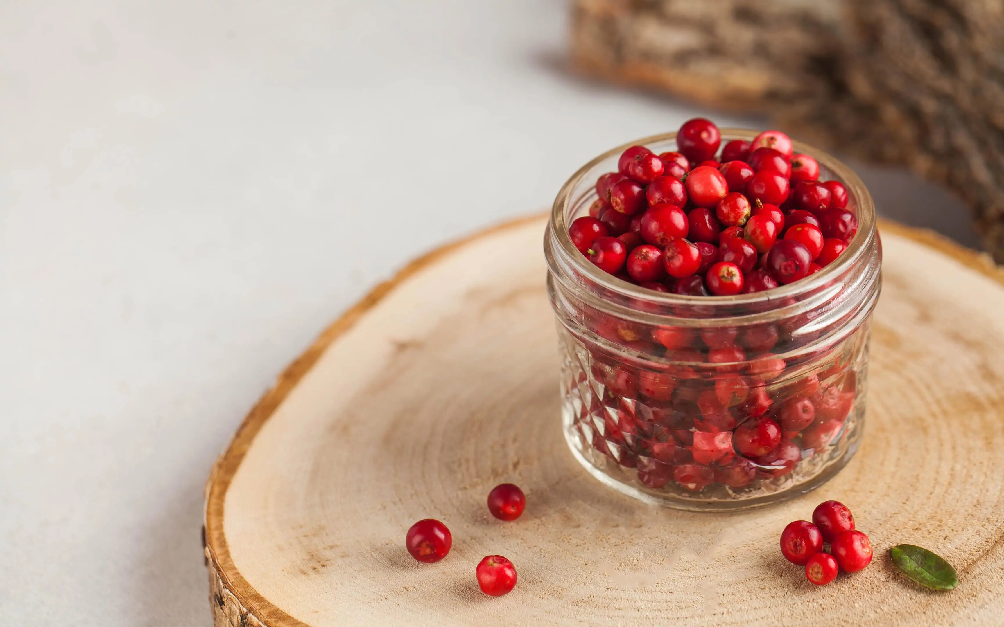 Fresh ripe cranberries in glass jar on wooden board