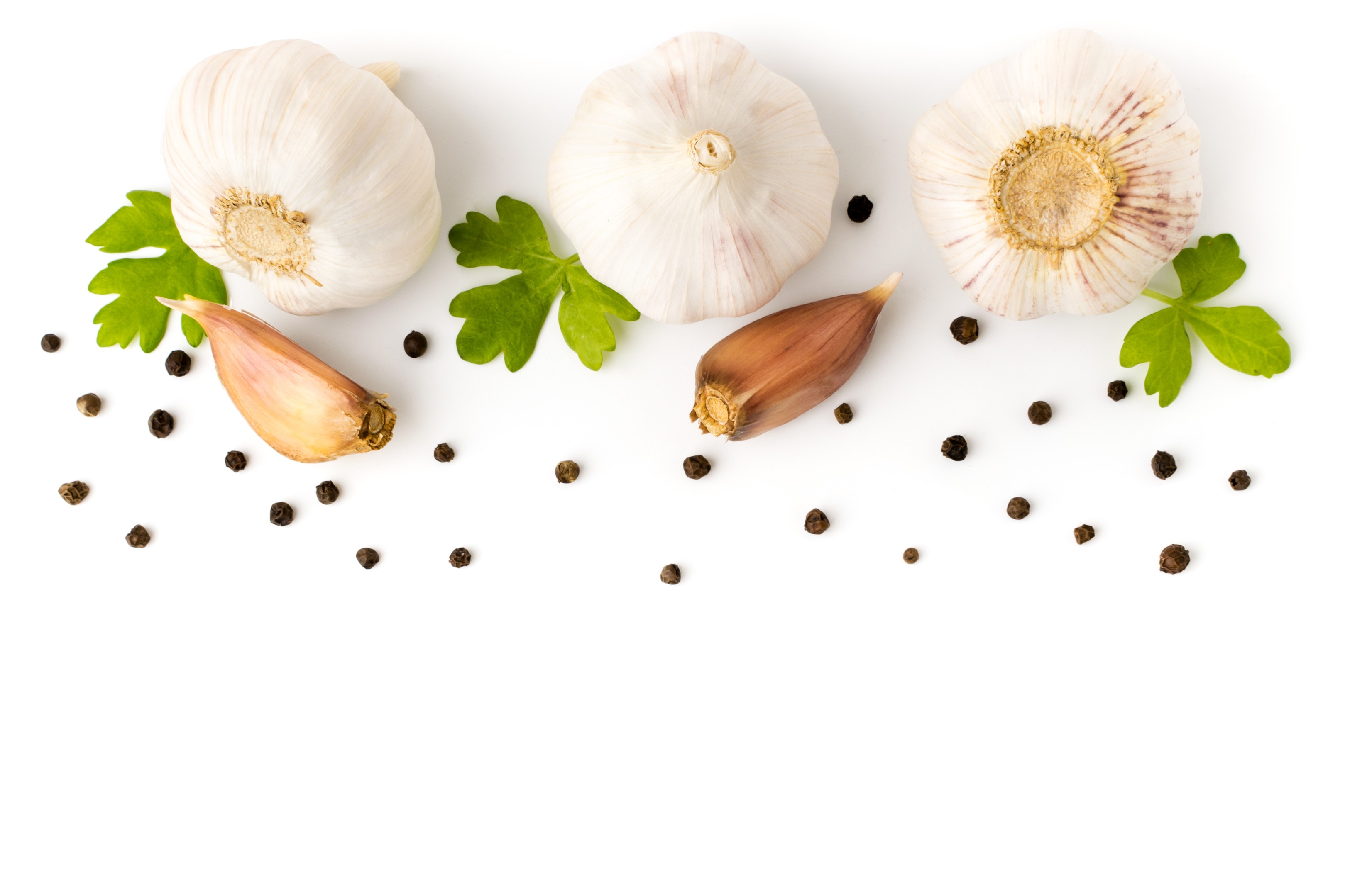 Garlic with parsley leaves and black pepper on white background