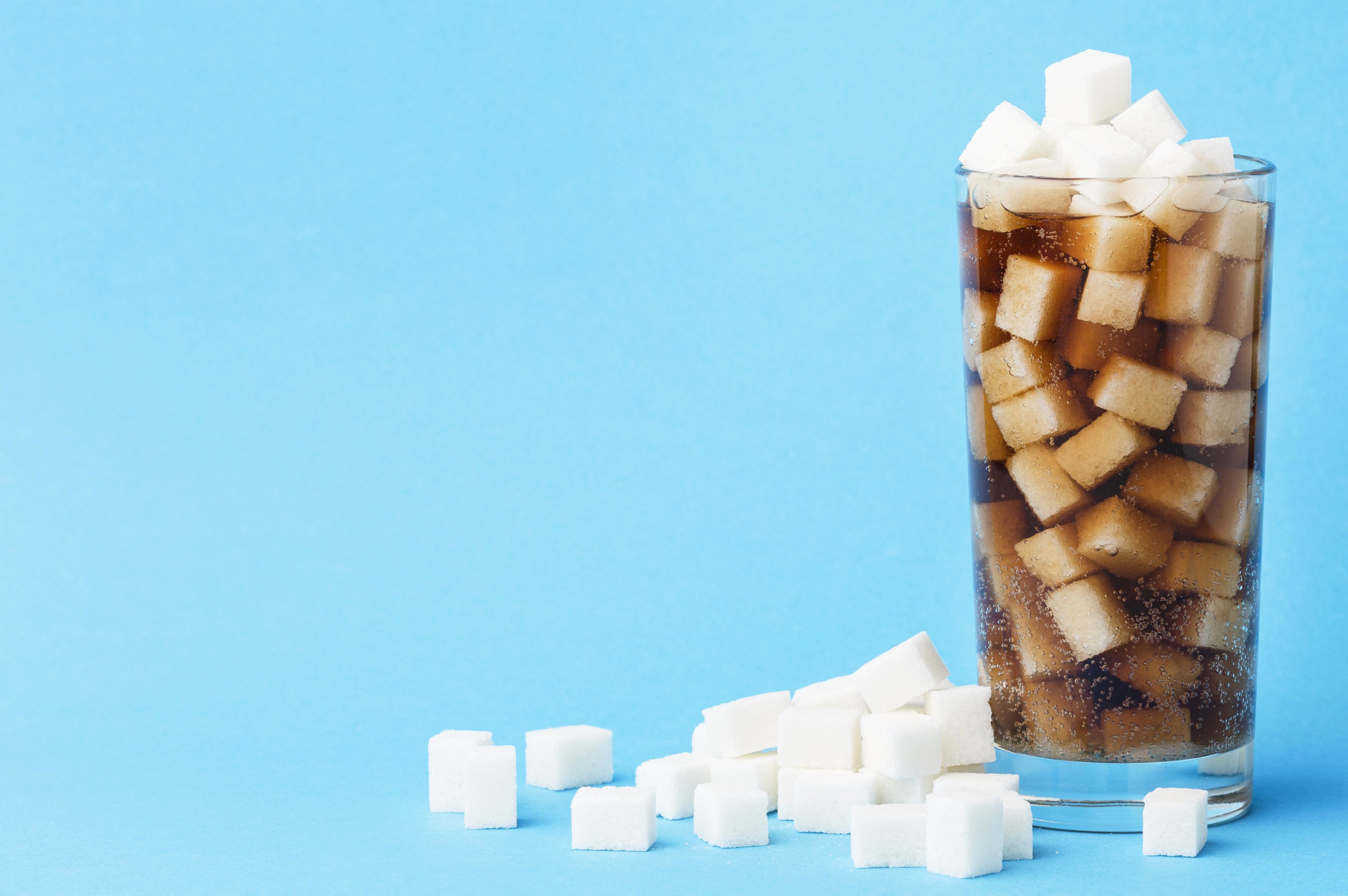 Glass of soft drink with sugar cubes