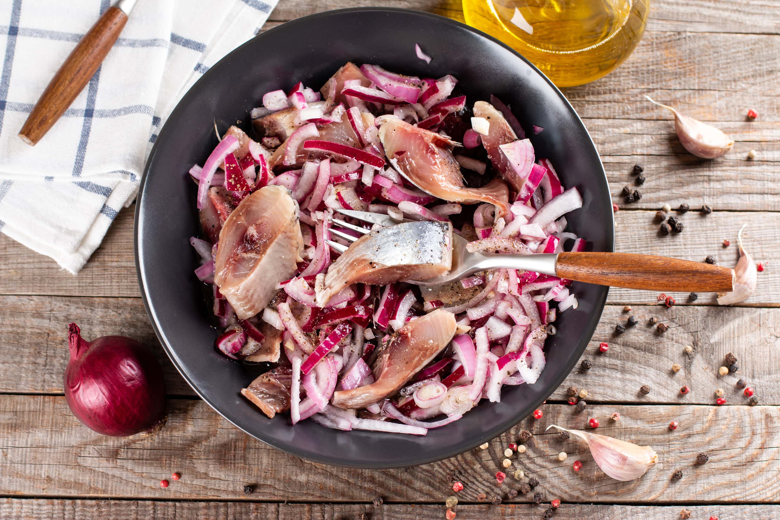Herring with red onions in black bowl