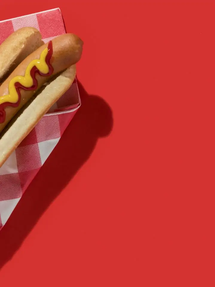 Hotdog with ketchup and mustard on red background