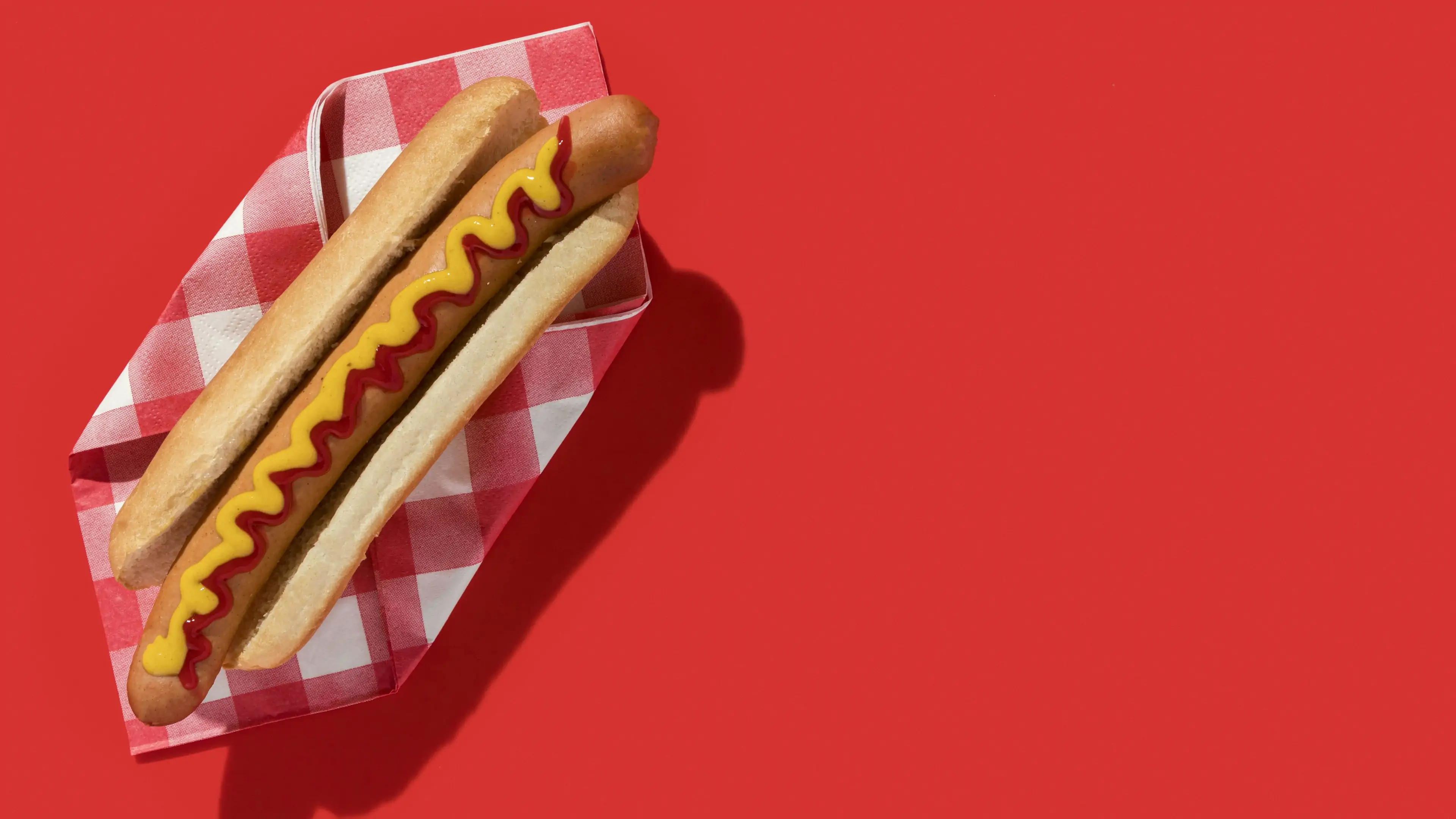 Hotdog with ketchup and mustard on red background