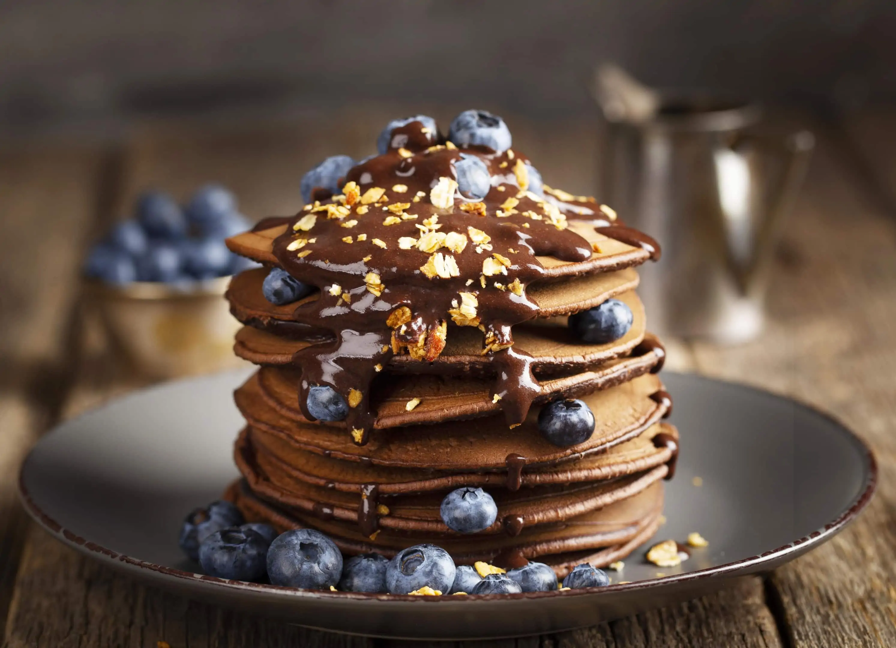 Oat flour pancakes tower with melted chocolate and blueberries