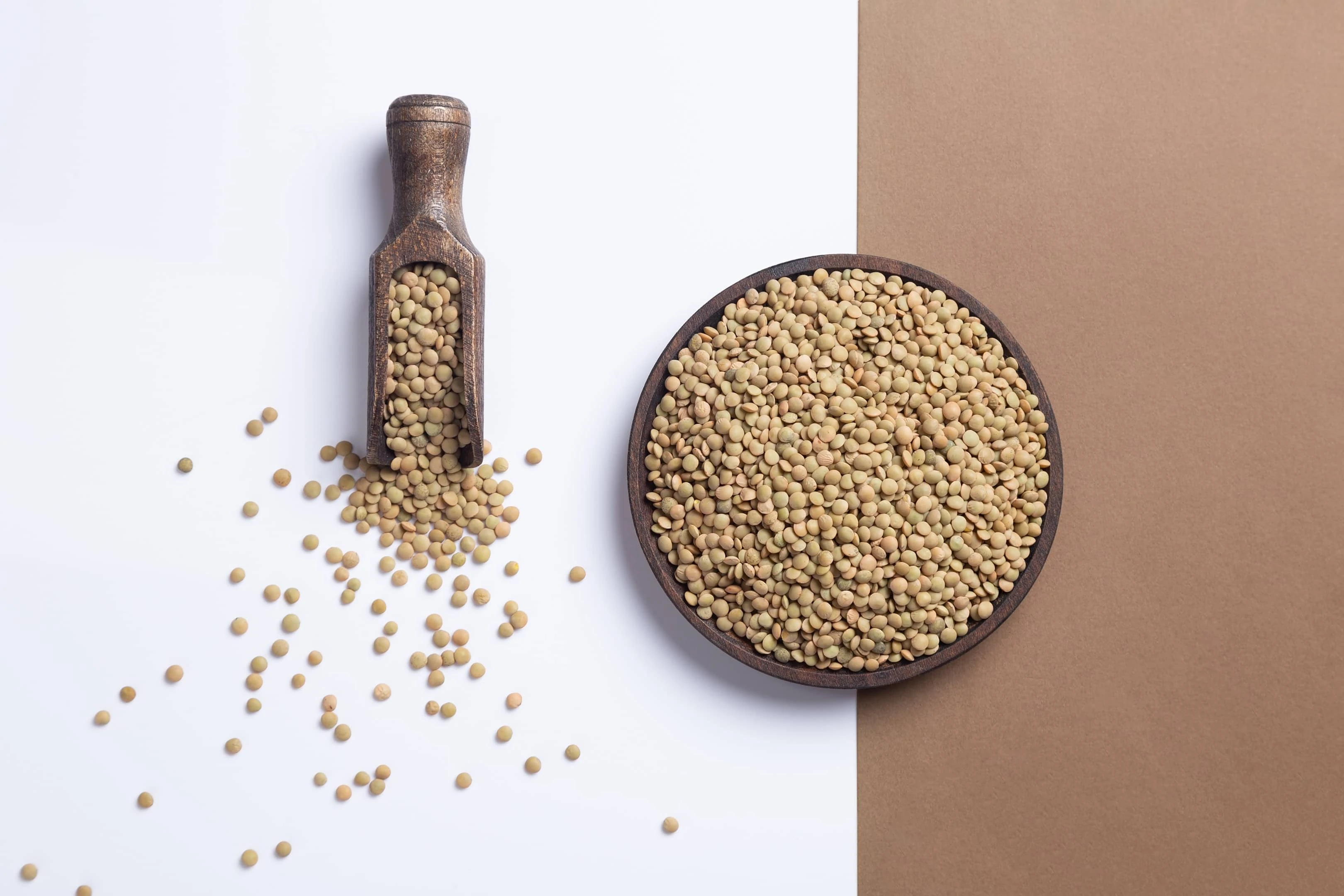 Raw lentils in wooden plate with wooden scoop
