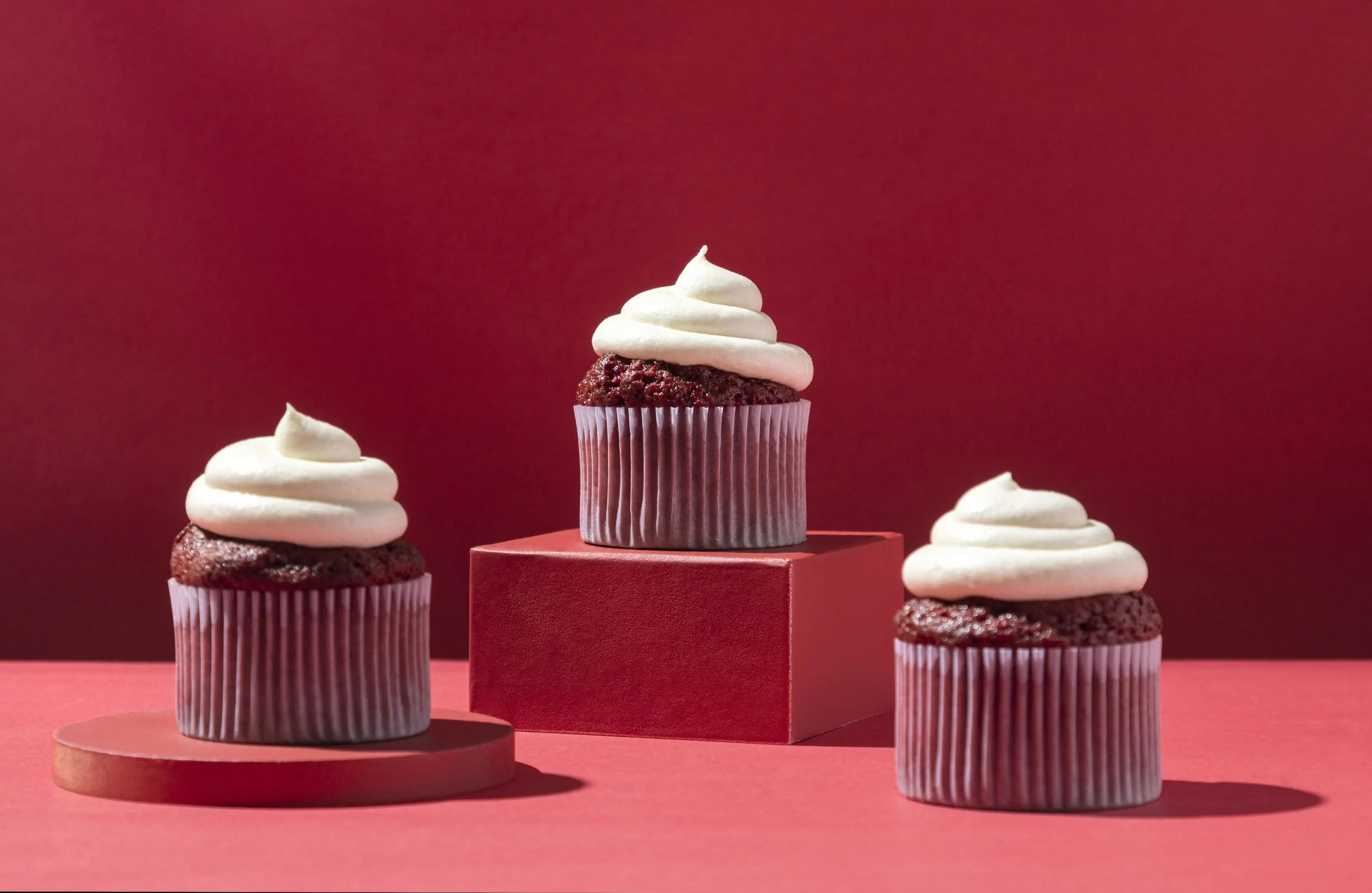 Red velvet cupcakes with cream on red background
