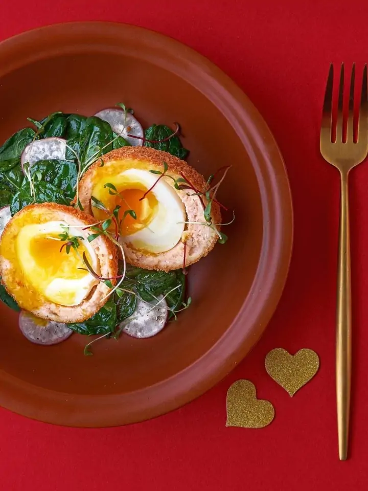 Scotch eggs with salmon radish and spinach on plate