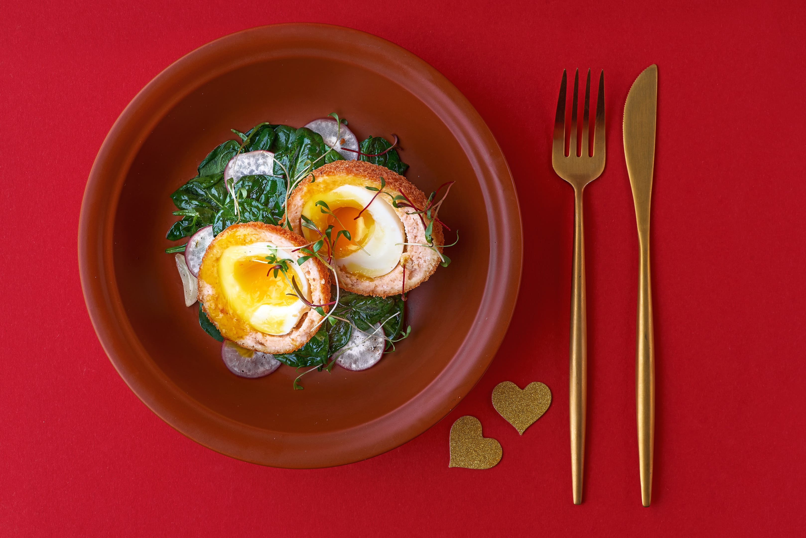 Scotch eggs with salmon radish and spinach on plate
