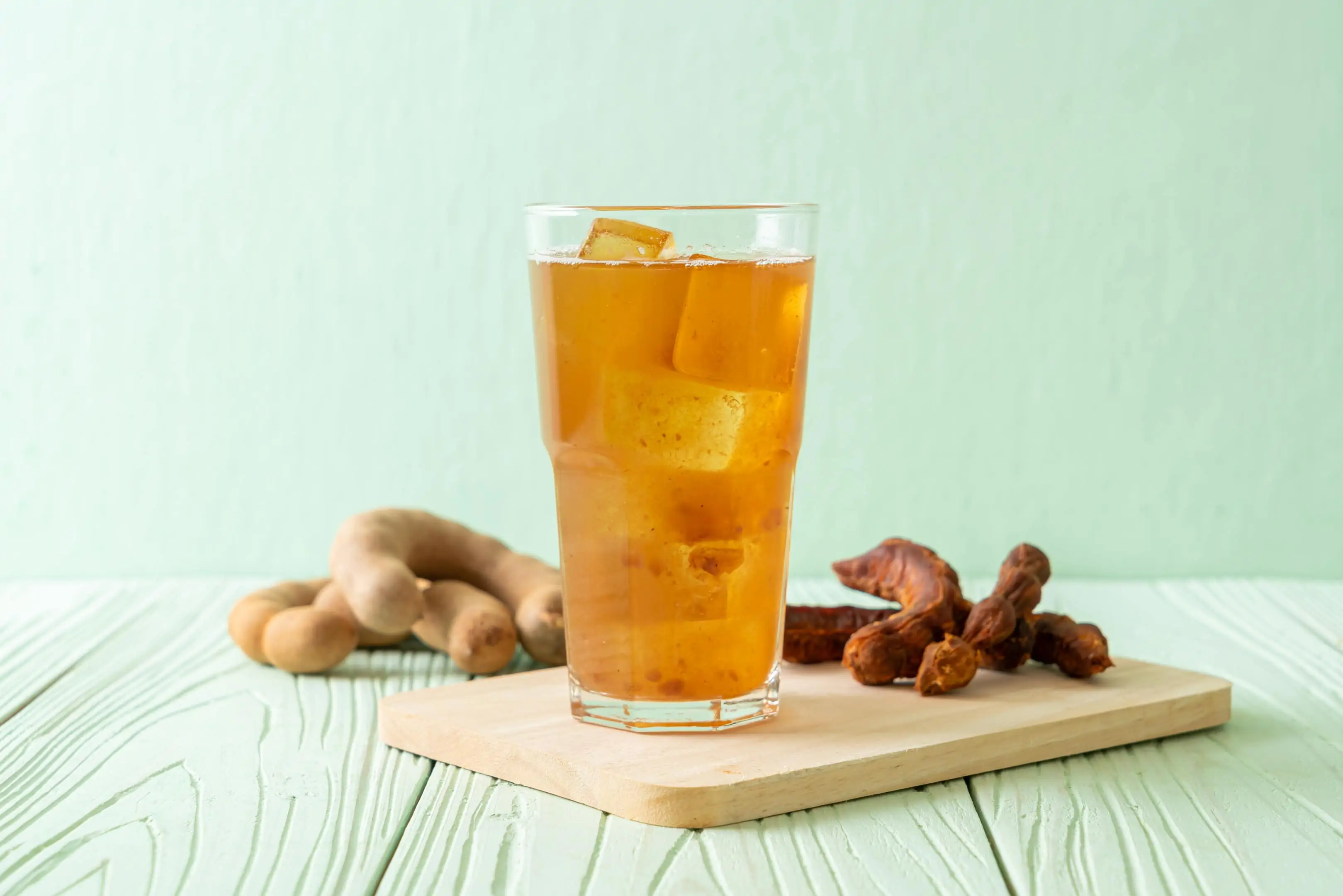Tamarind and turmeric drink with ice cubes on wooden board