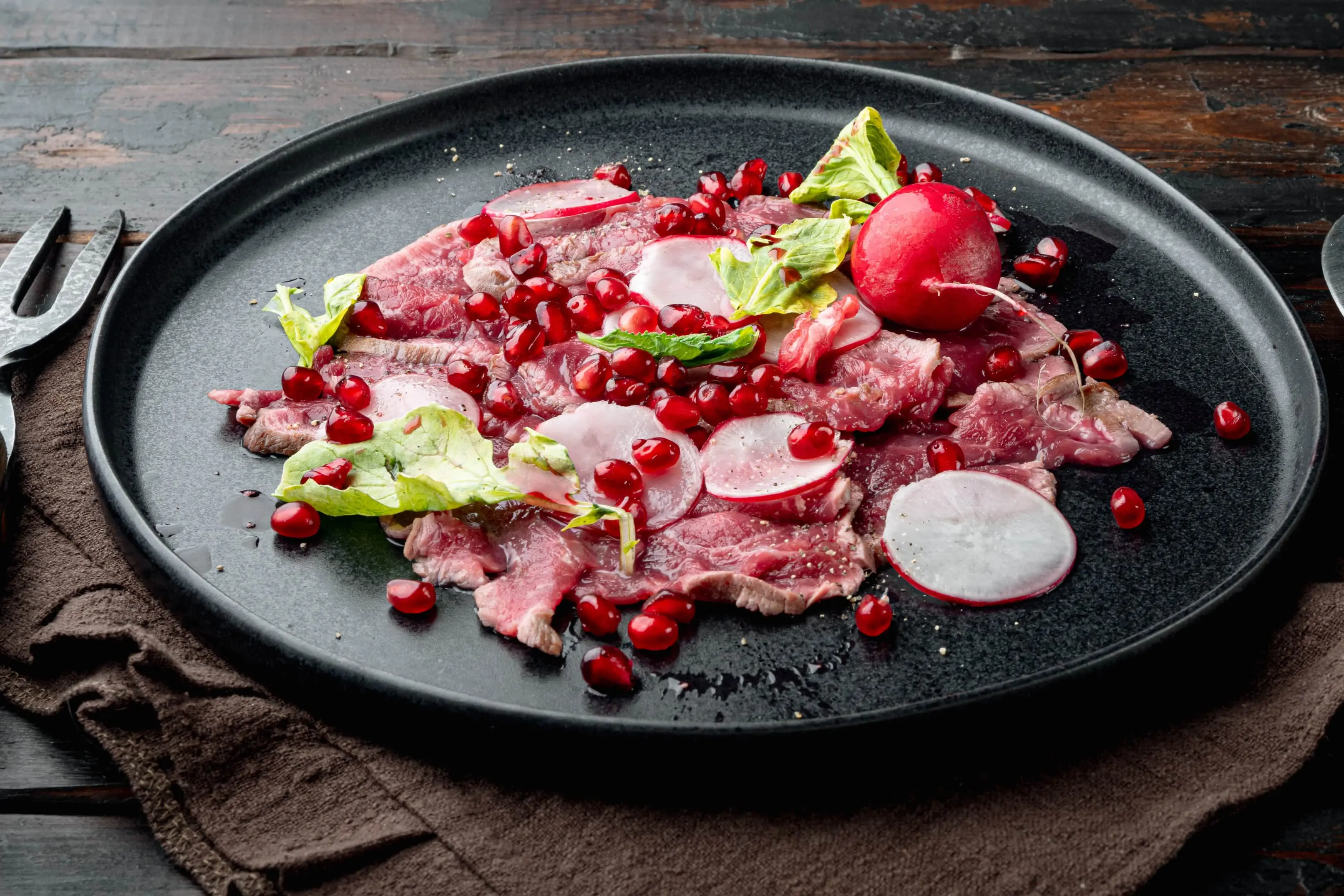 Beef carpaccio with radish, pomegranate seeds and olive oil