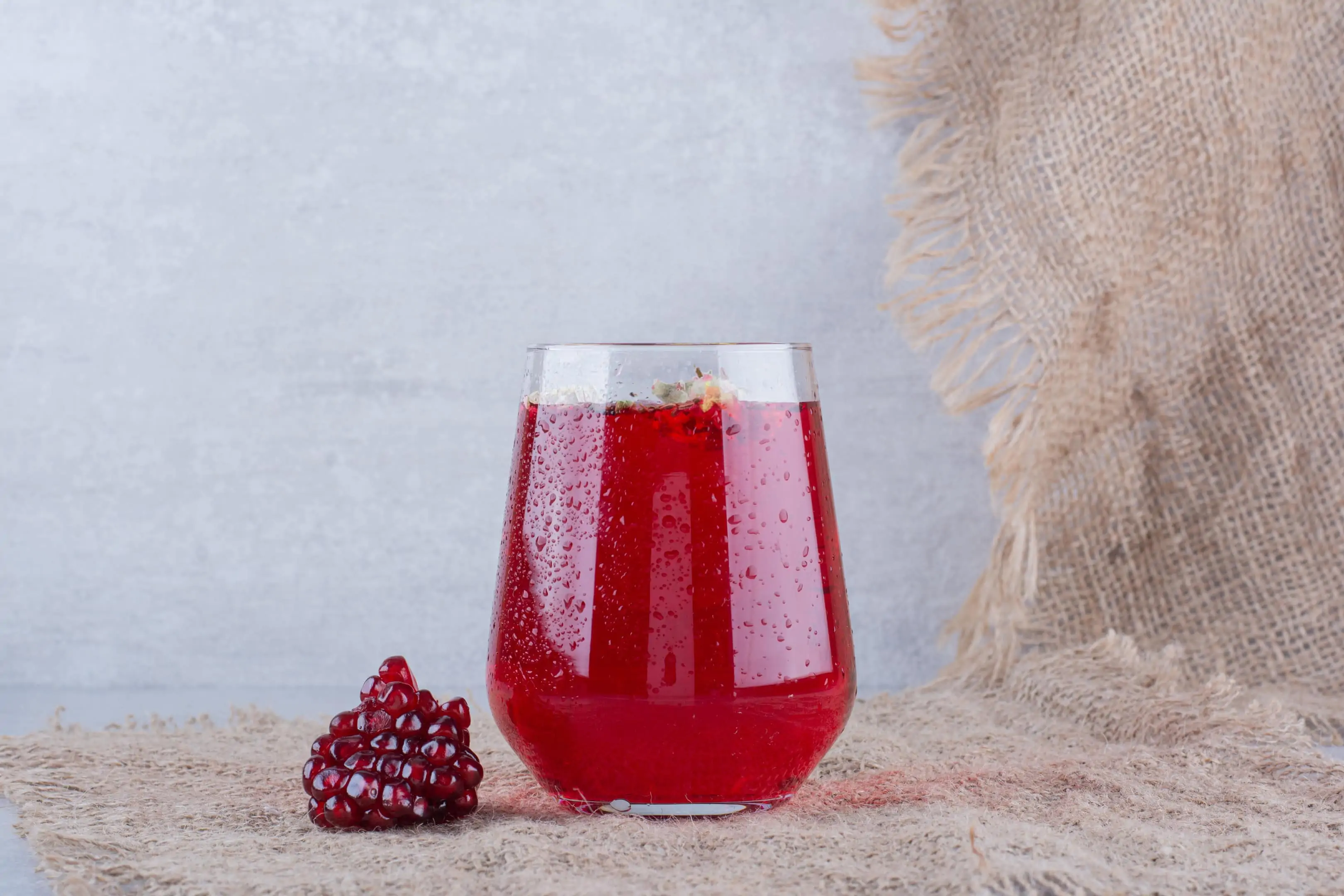 A glass of pomegranate juice with pomegranate seeds