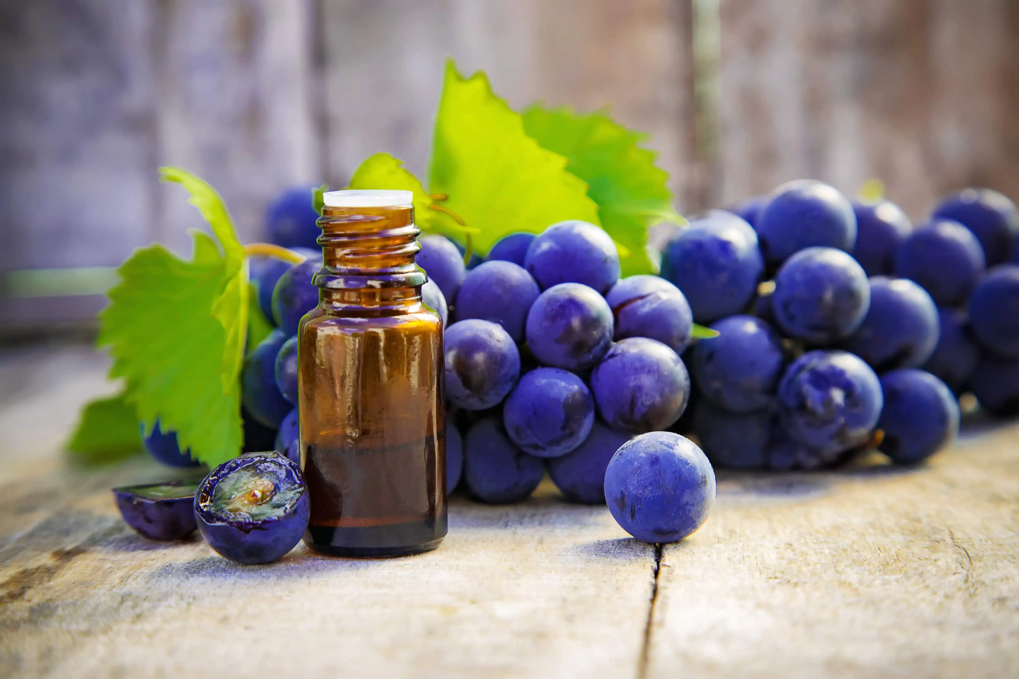 Grape seed extract in a small glass bottle with fresh grapes