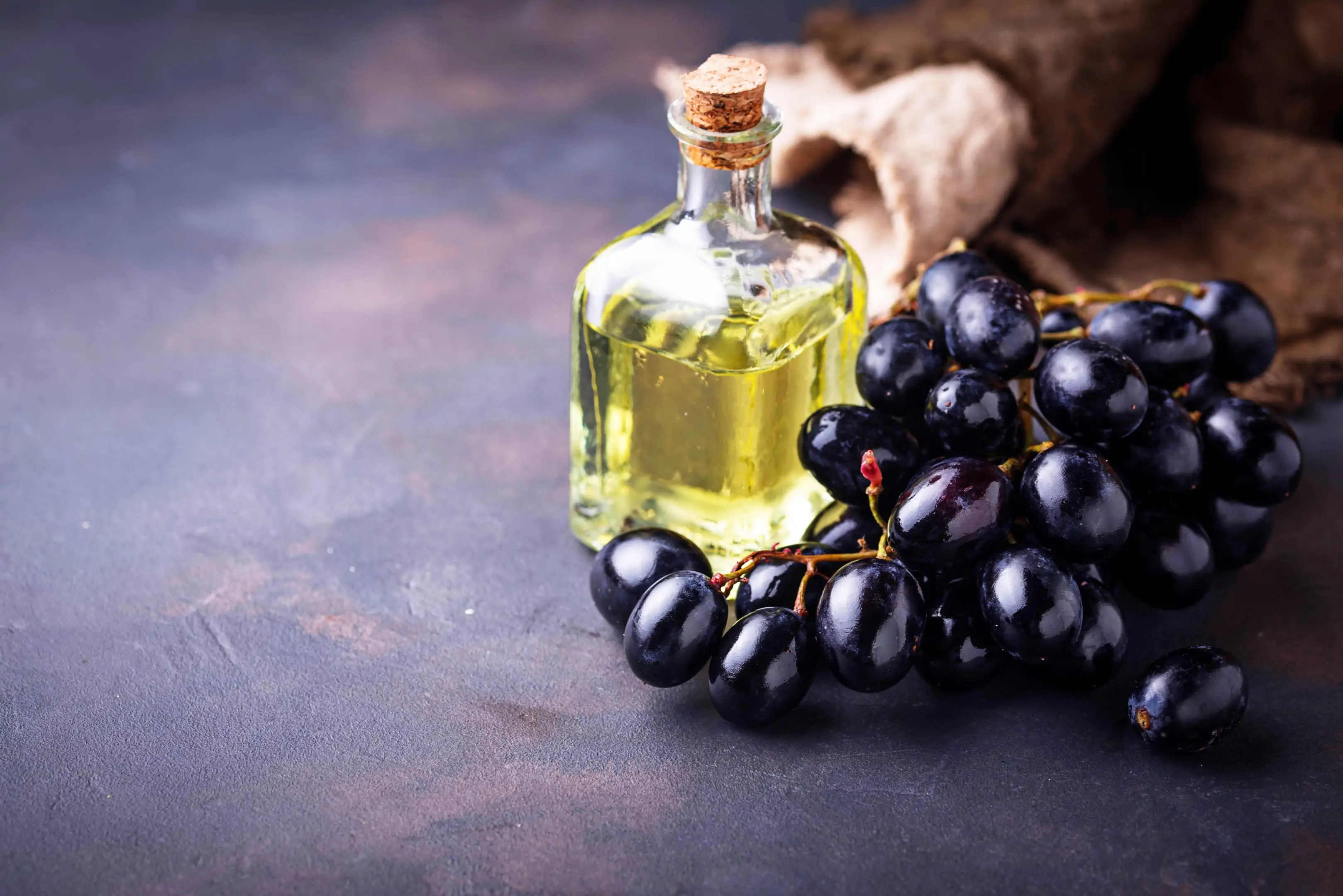Grape seed extract in a small glass bottle with fresh grapes