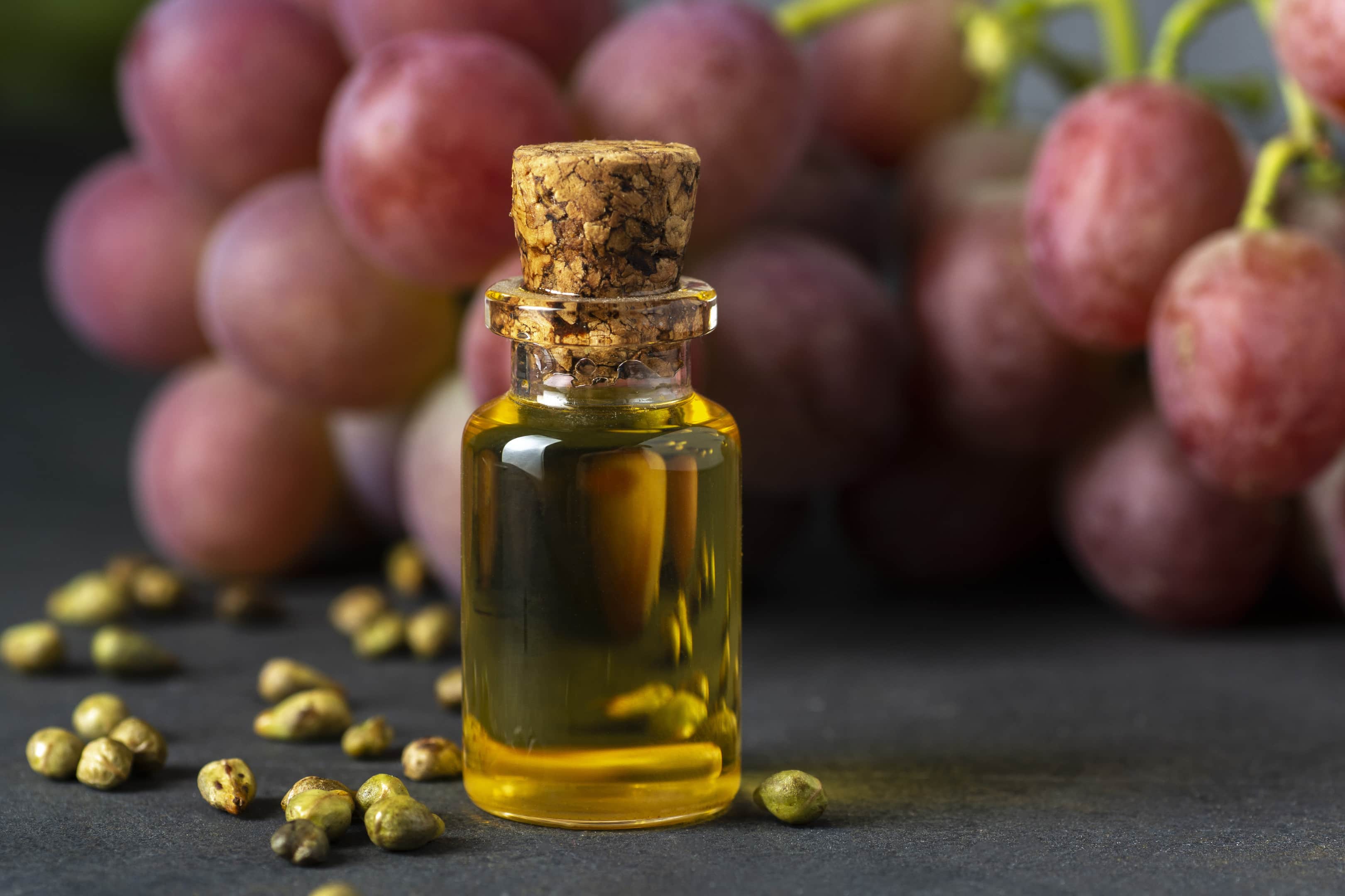 Grape seed oil extract in glass bottle and fresh grapes