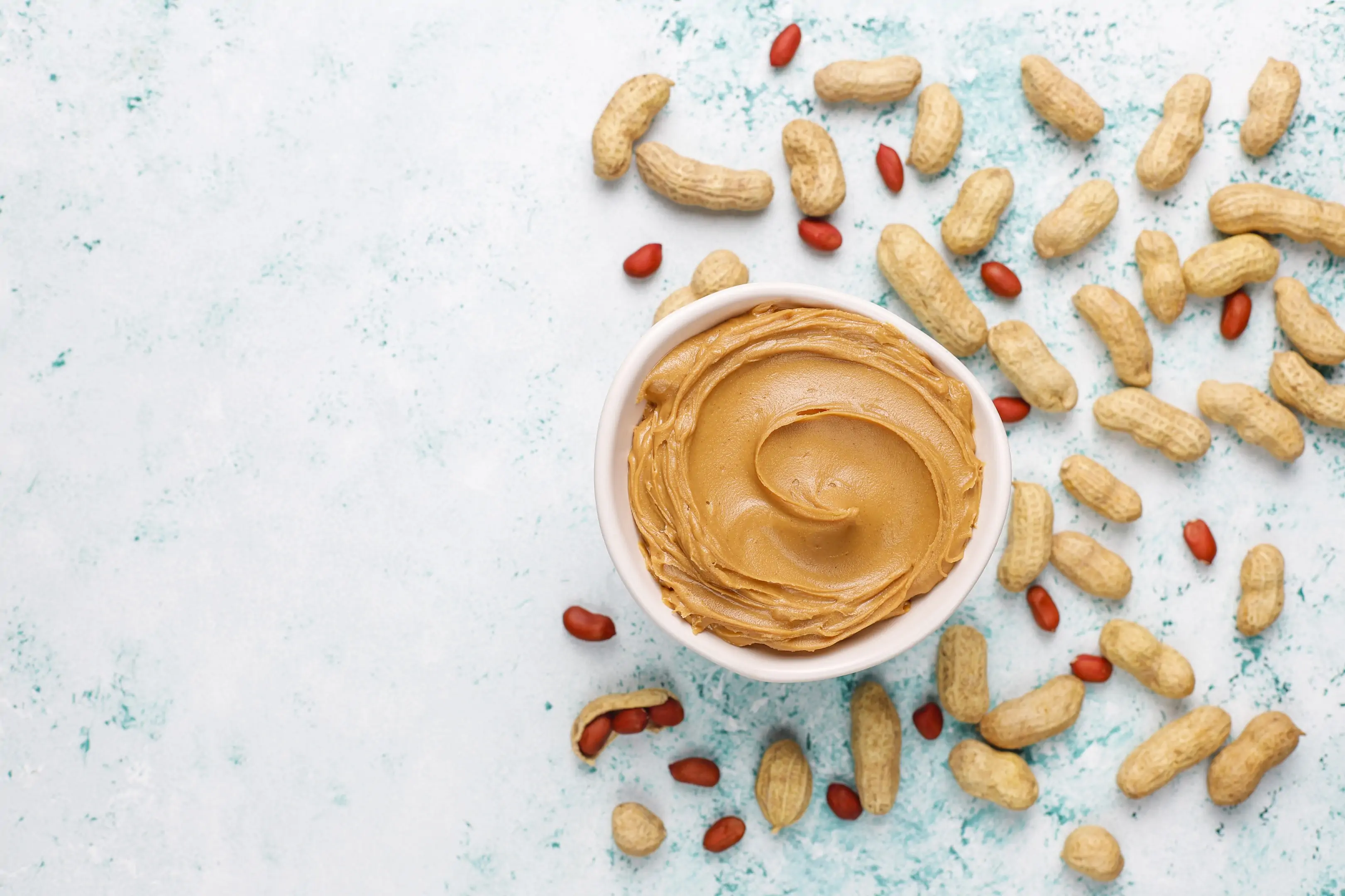 Homemade peanut butter with peanuts on a grey concrete table