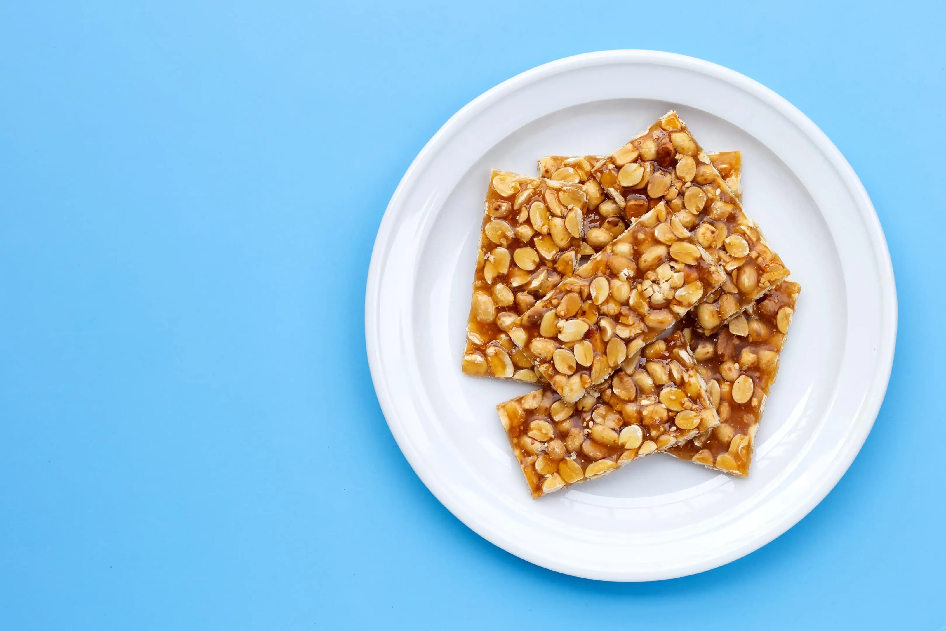 Kadalai mittai — peanuts and jaggery bars in a plate on blue background