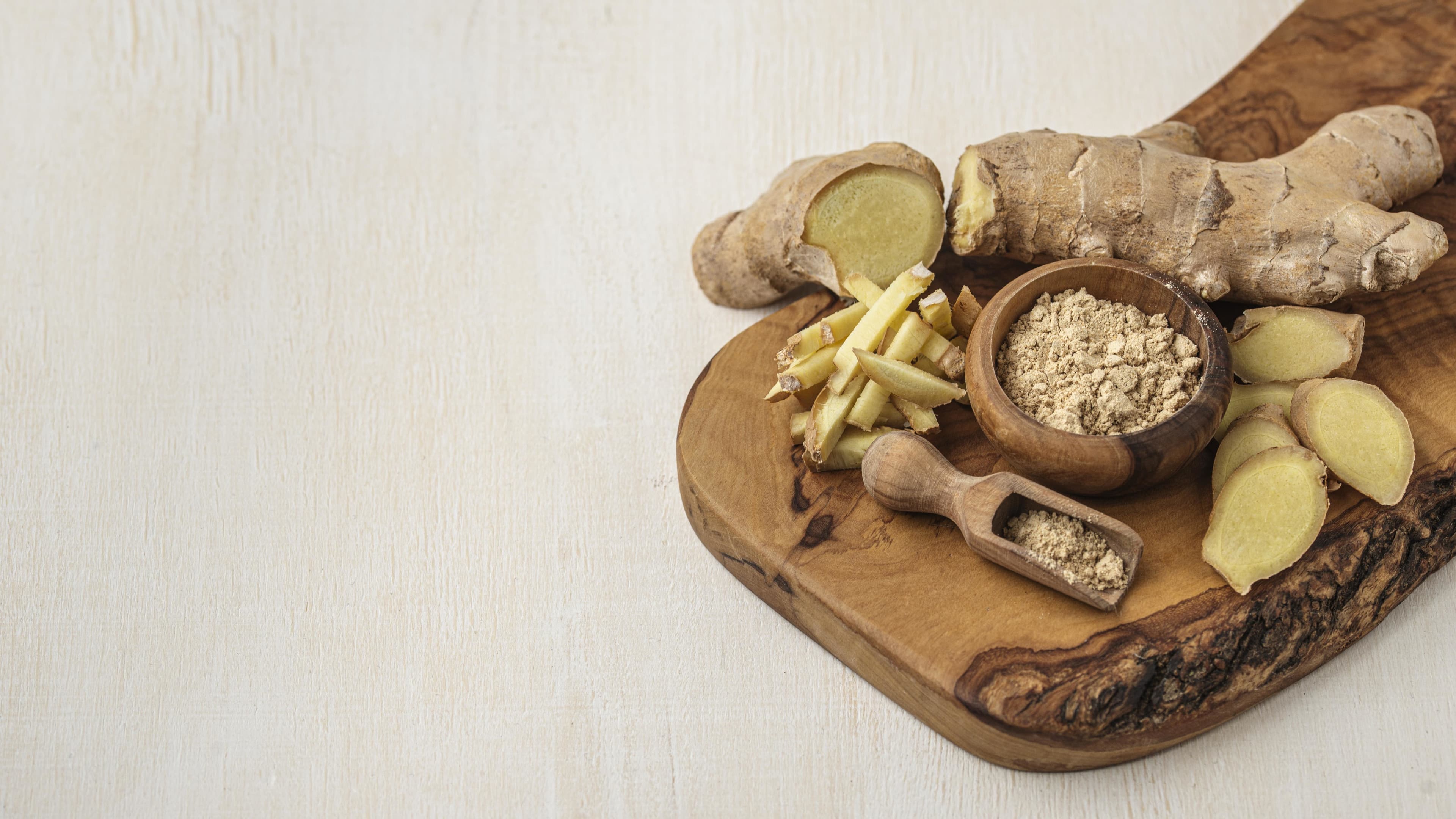 Assortment of fresh and powdered ginger on wooden board