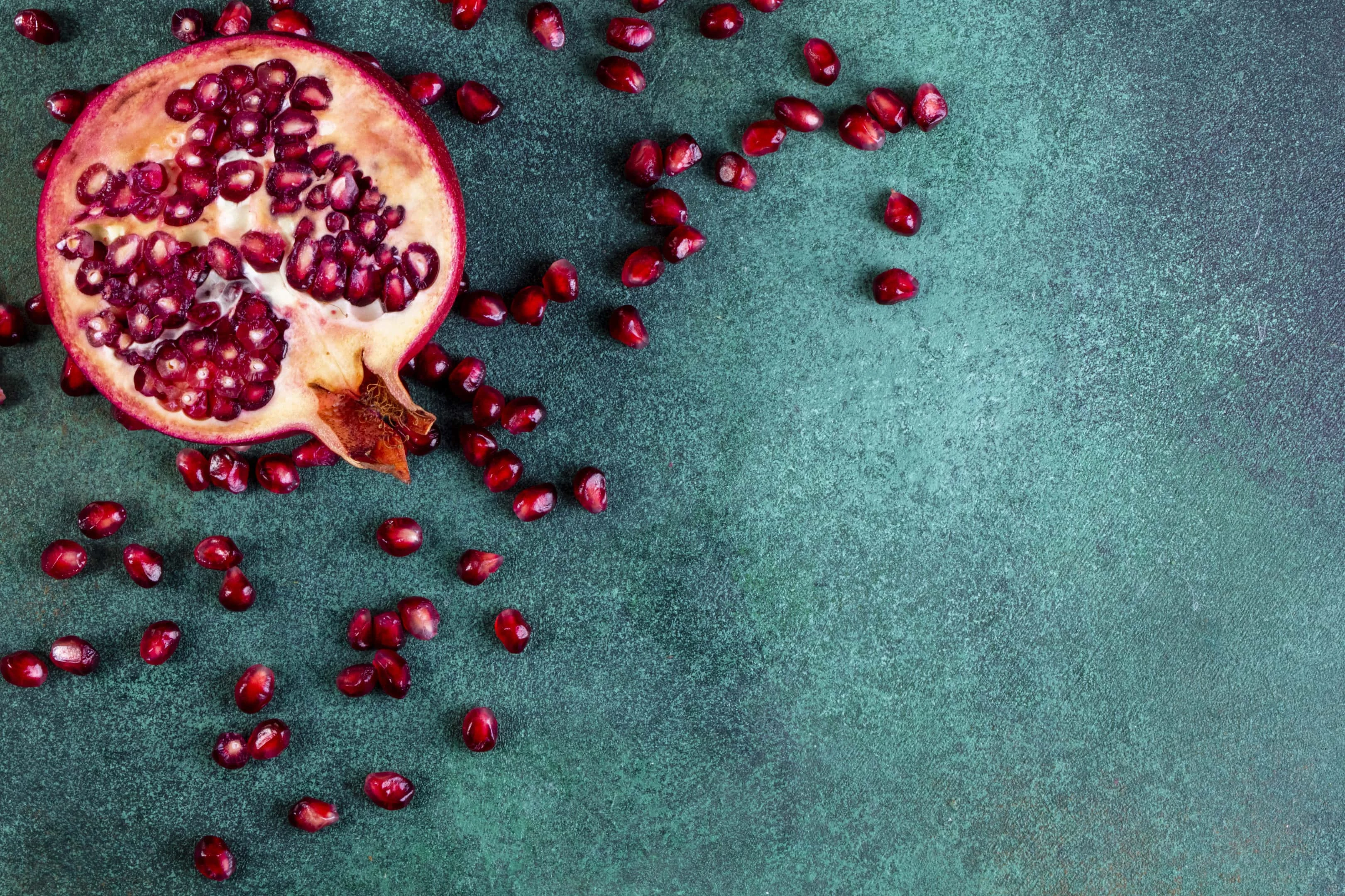 Chopped half of pomegranate on green table