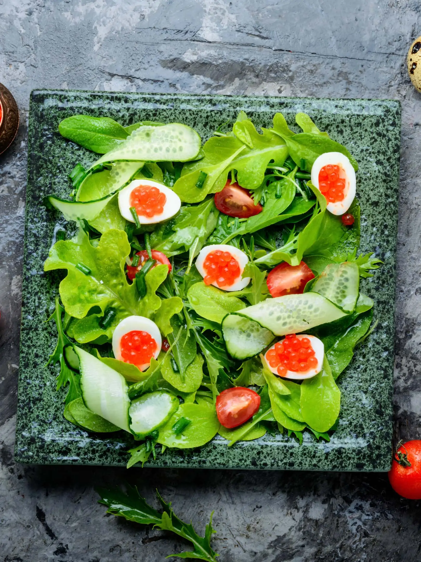 Spring vegetable salad with greens, cucumber, egg and red caviar
