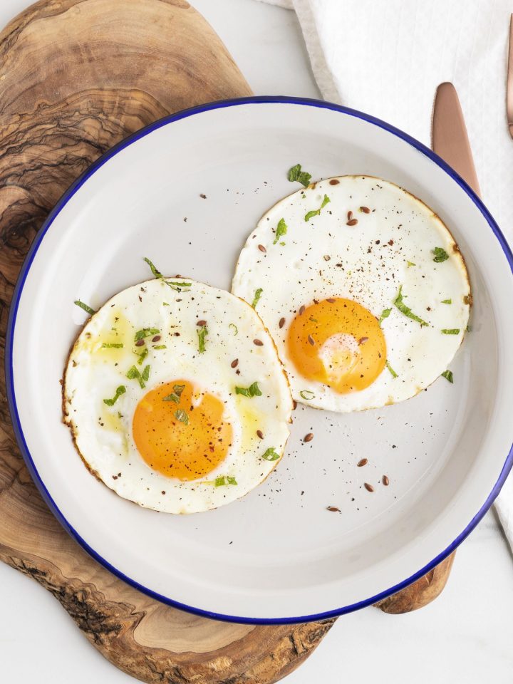 Fried eggs plate with cutlery on wooden board