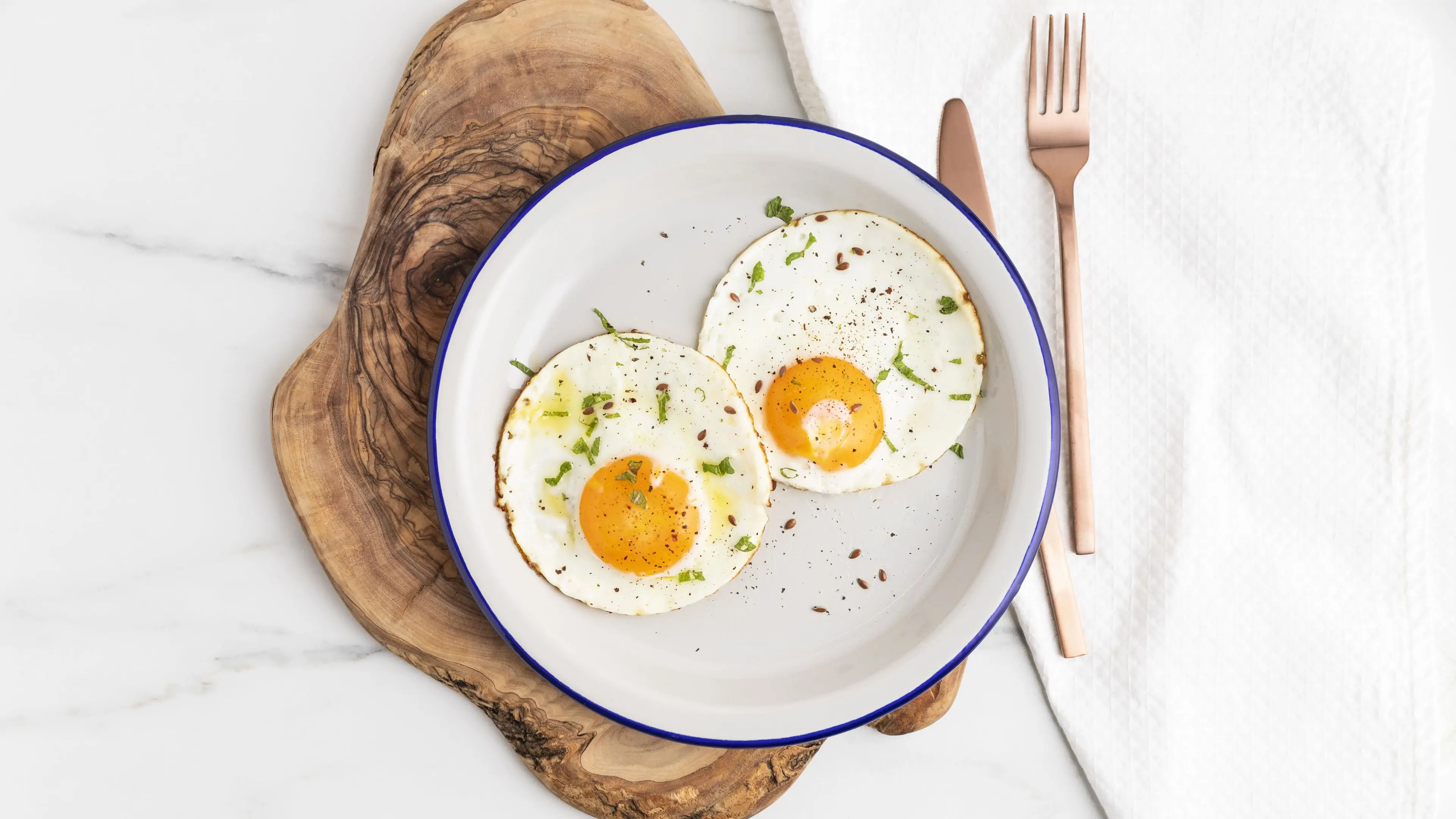 Fried eggs plate with cutlery on wooden board