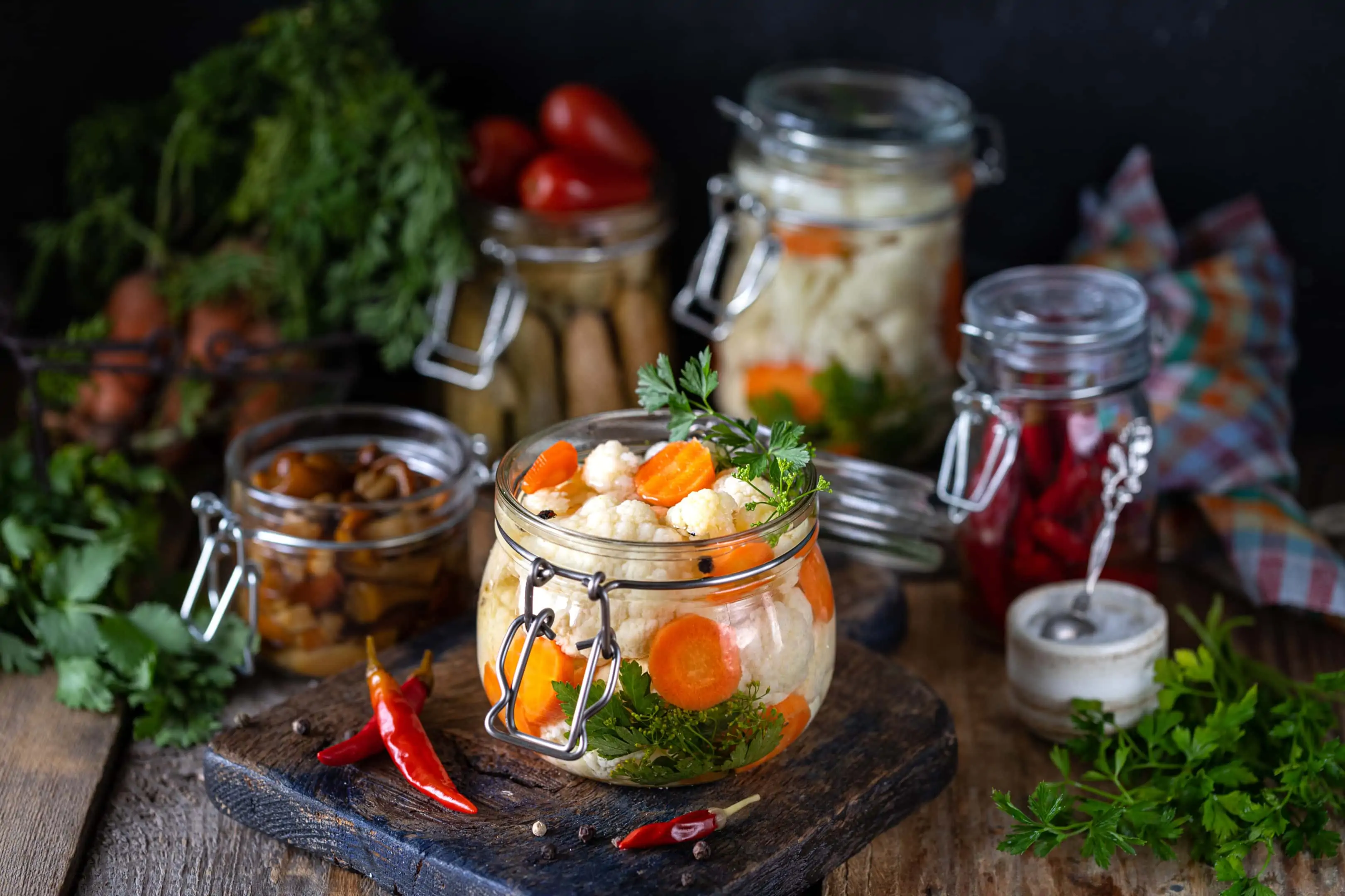 Fermented cauliflower with carrots in a glass jar on wooden table