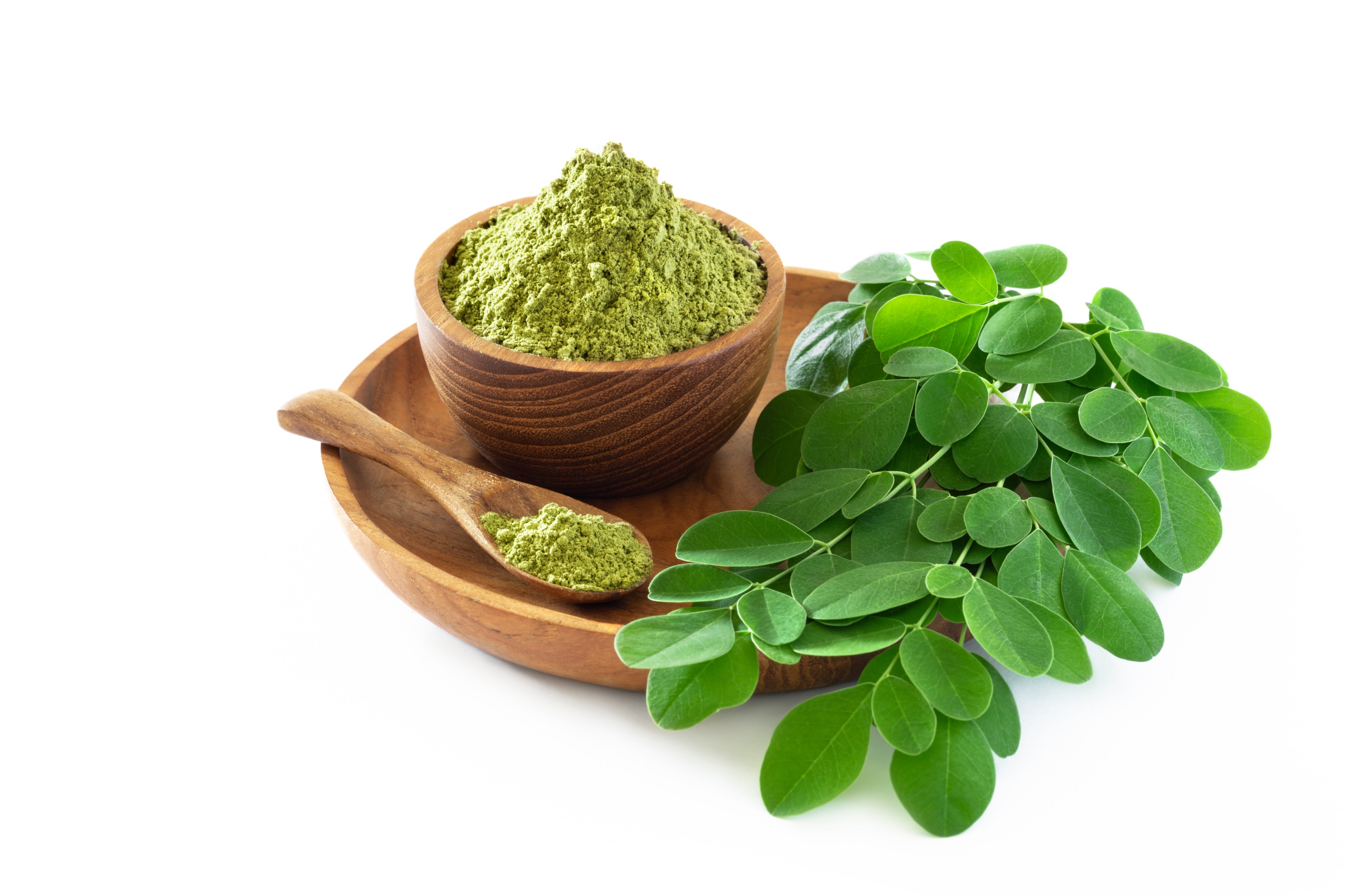 Moringa powder in wooden bowl with fresh moringa leaves