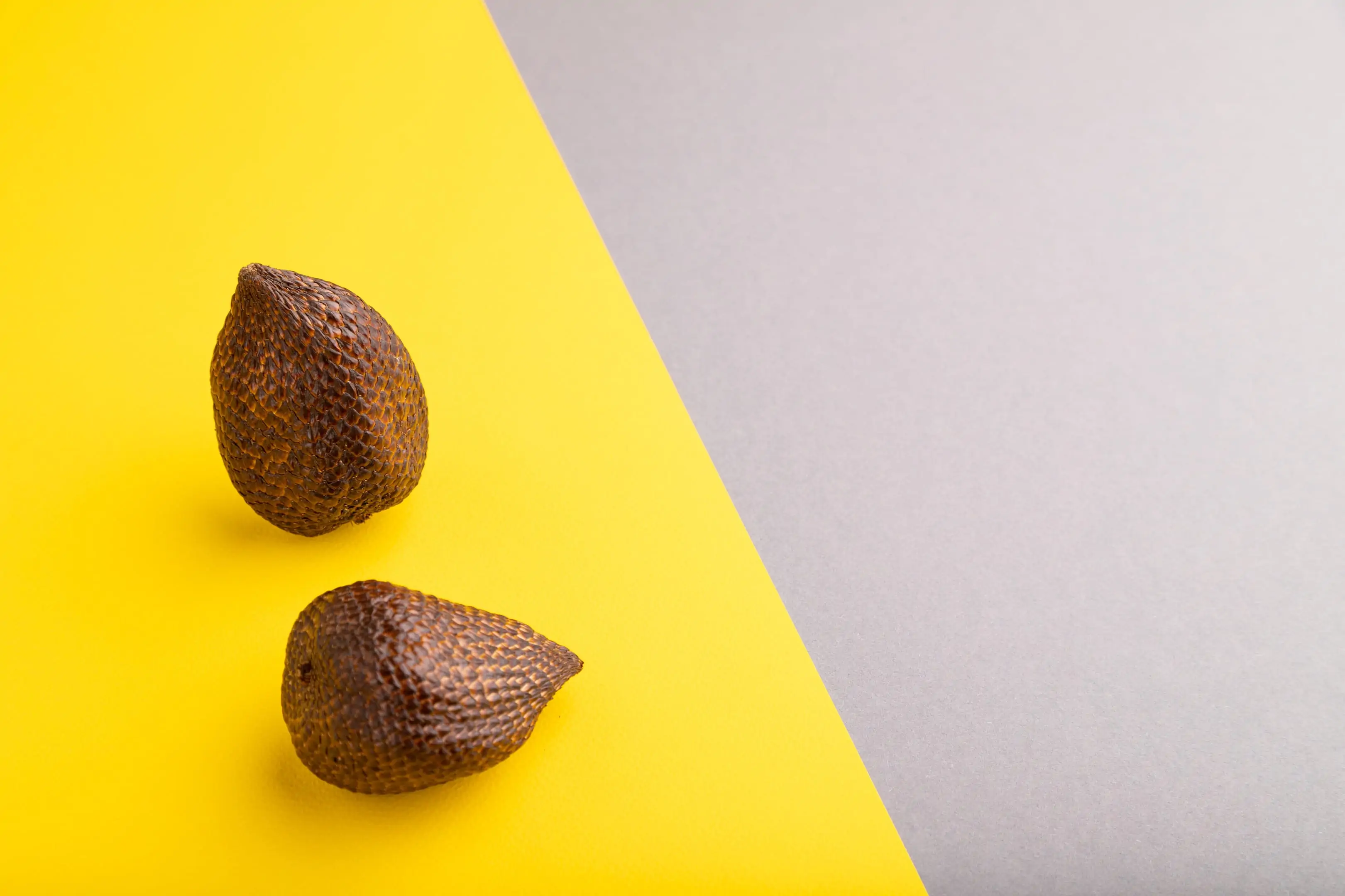 Salak — snake fruit — on a gray and yellow background