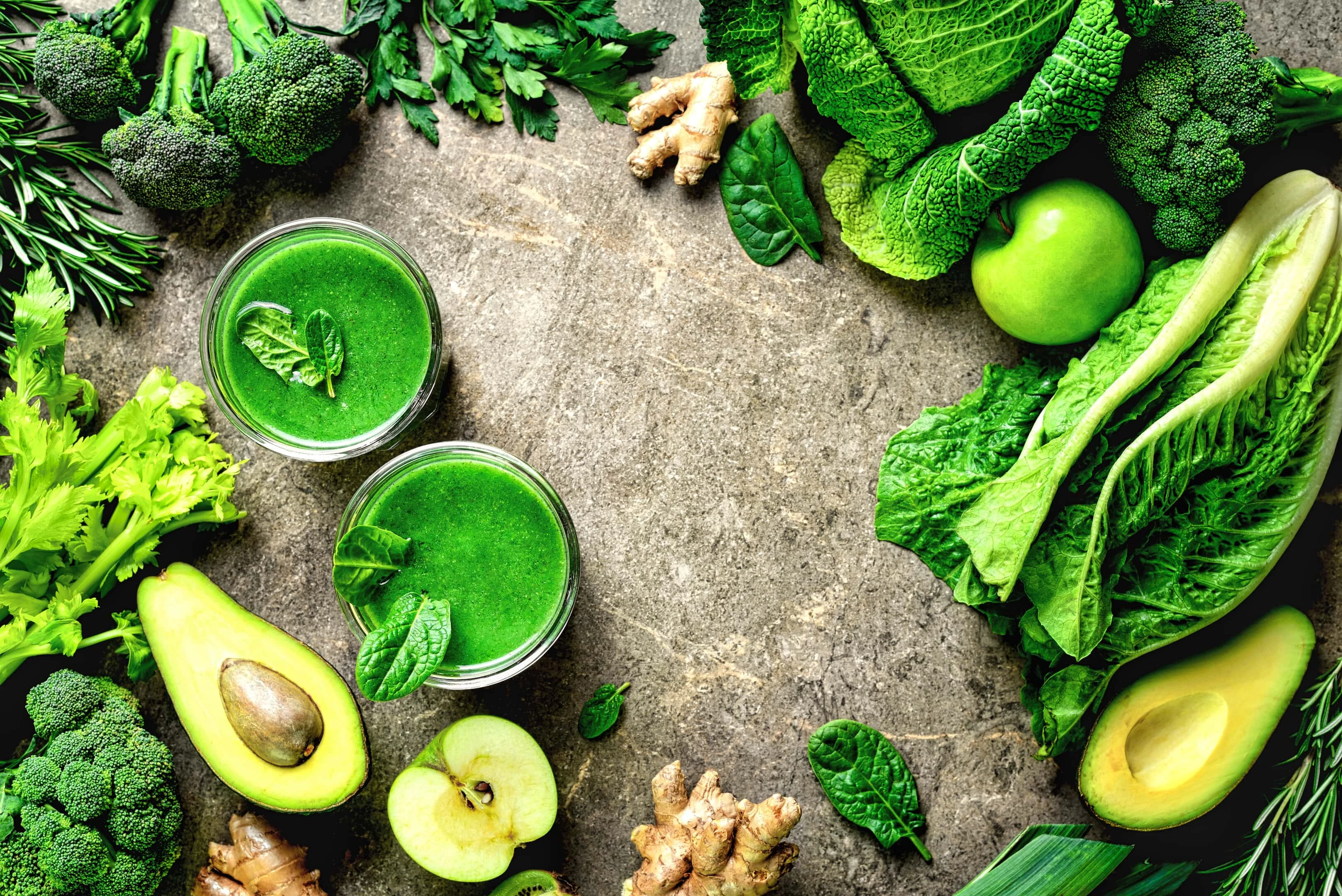 Green fruits and dark green leafy vegetables with two green smoothies glasses