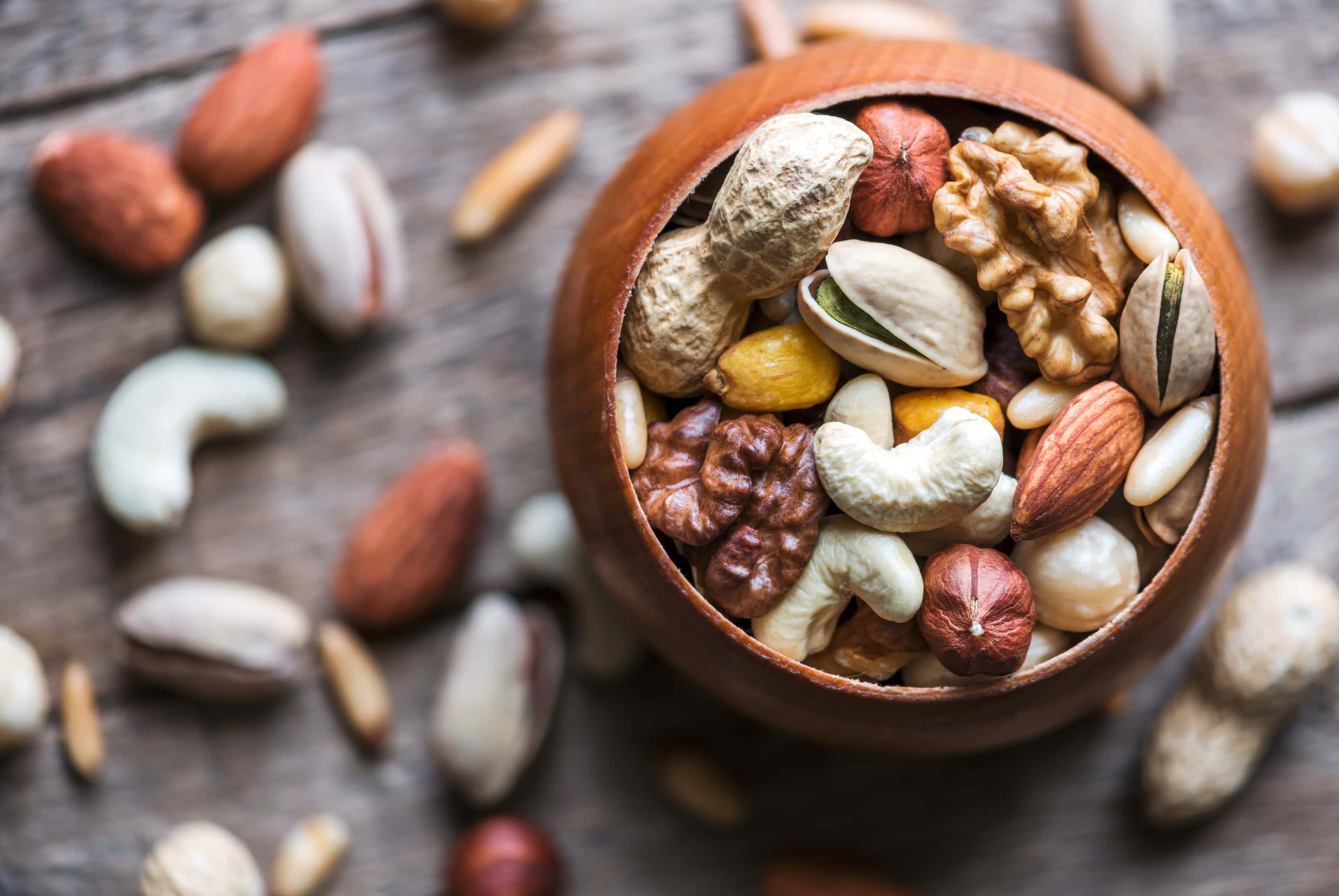 Dried mixed nuts in wooden bowl closeup