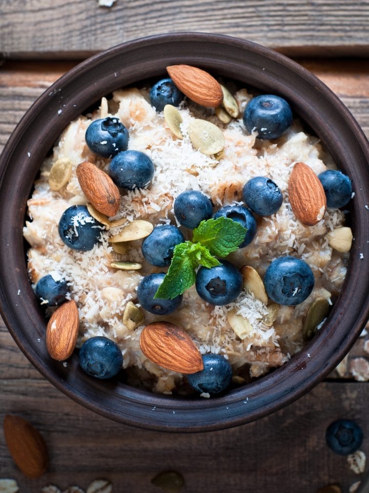 Oatmeal with blueberries, almonds, coconat and seeds at rustic wooden table