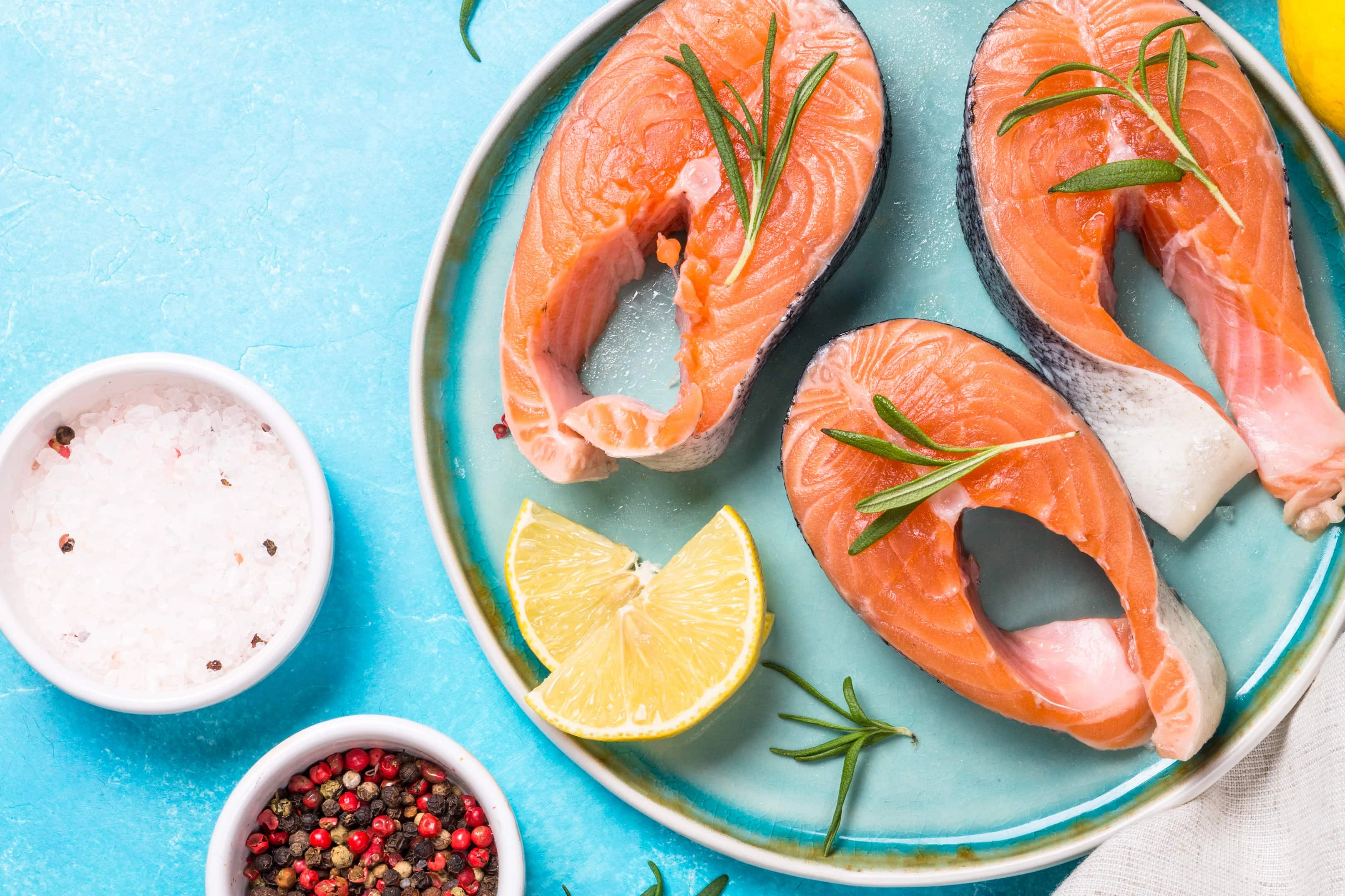 Raw Salmon fish steak on blue plate with ingredients for cooking