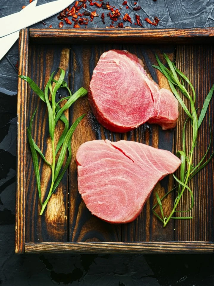 Fresh raw tuna steak and tarragon on kitchen table