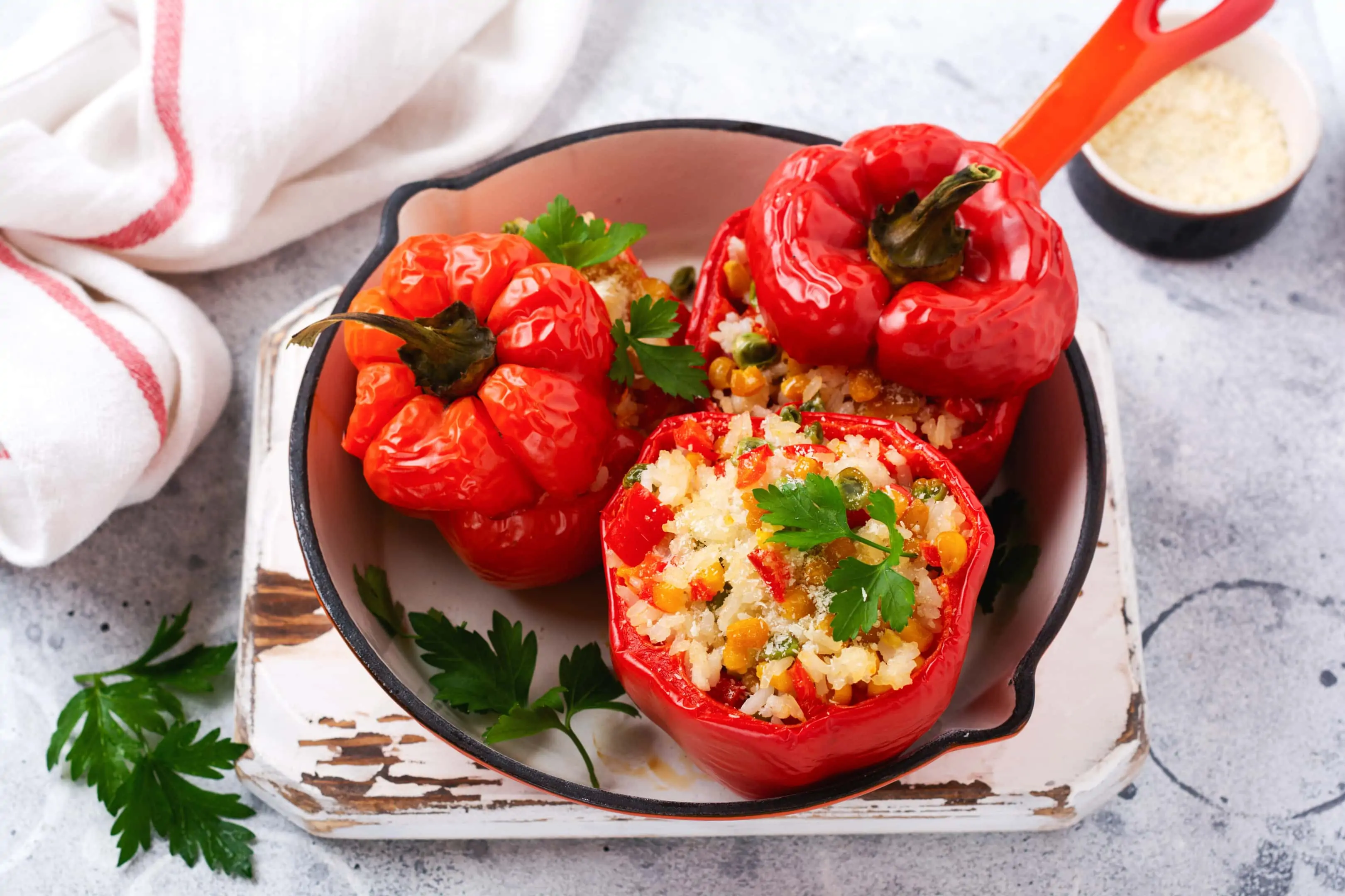 Red bell peppers stuffed with rice and vegetables on cast iron pan