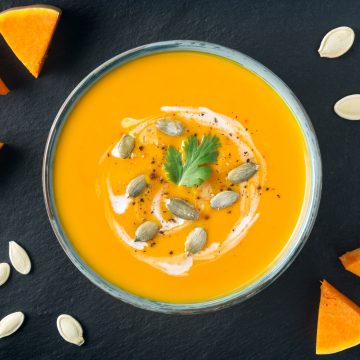 Creamy butternut squash soup with butternut squash slices and seeds