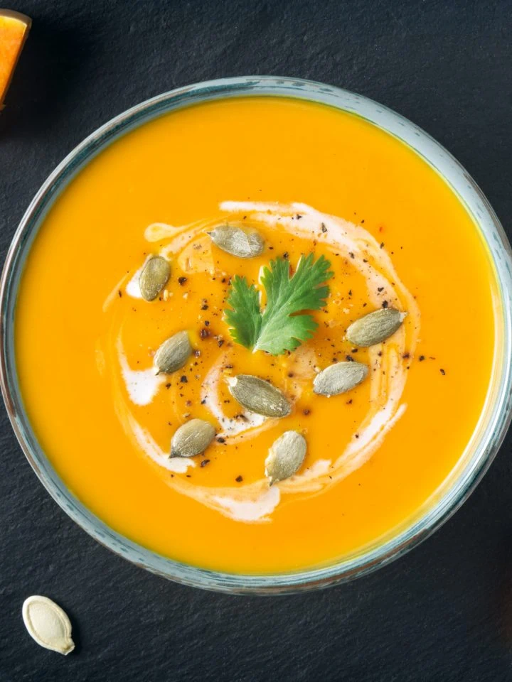 Creamy butternut squash soup with butternut squash slices and seeds