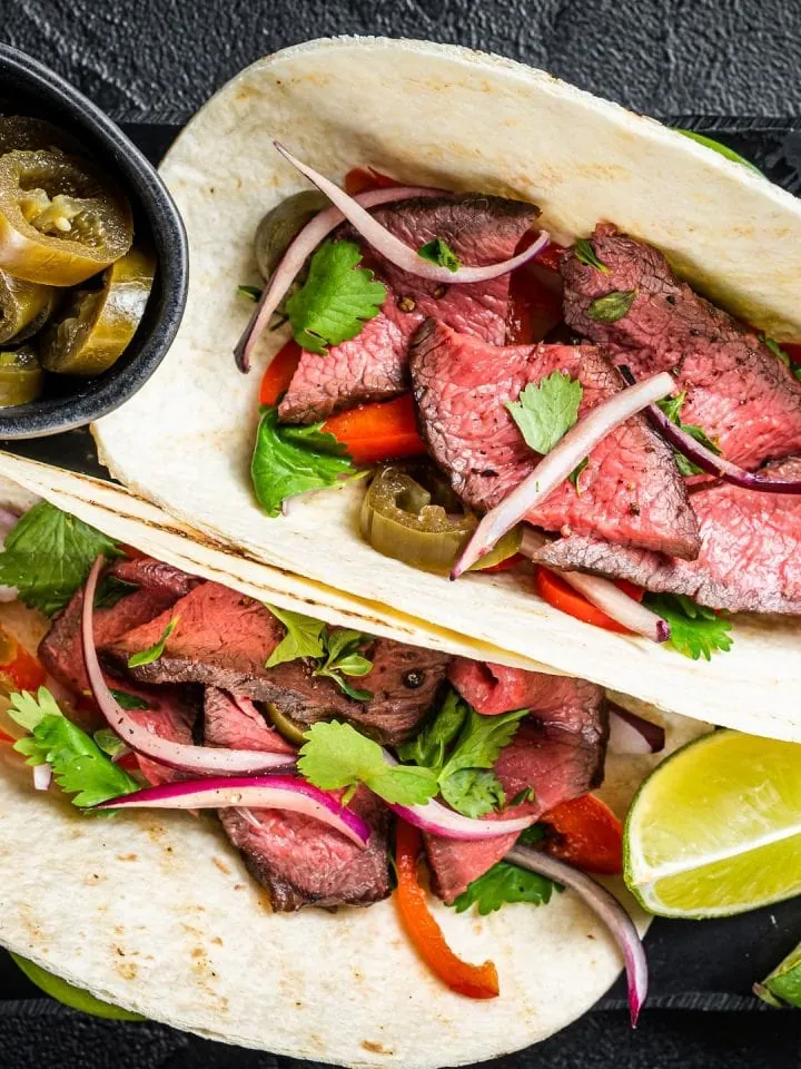 Mexican Lupe Tortilla fajita with meat, cilantro, green sauce, jalapenos, and onion