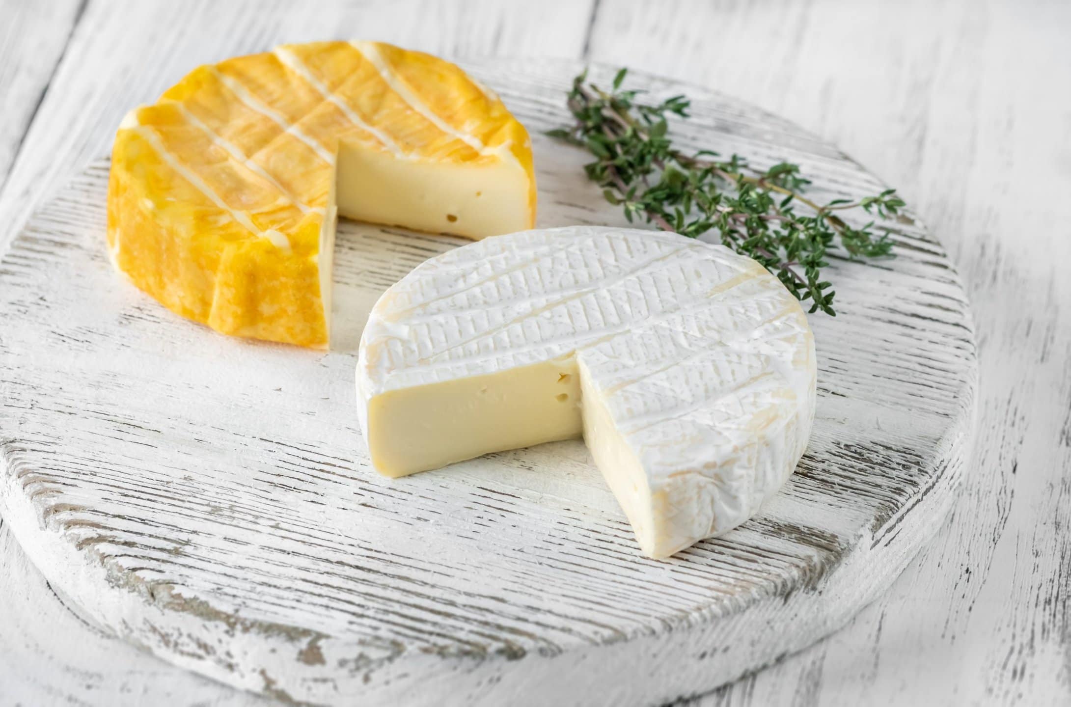 Two camembert cheese wheels on a cutting board